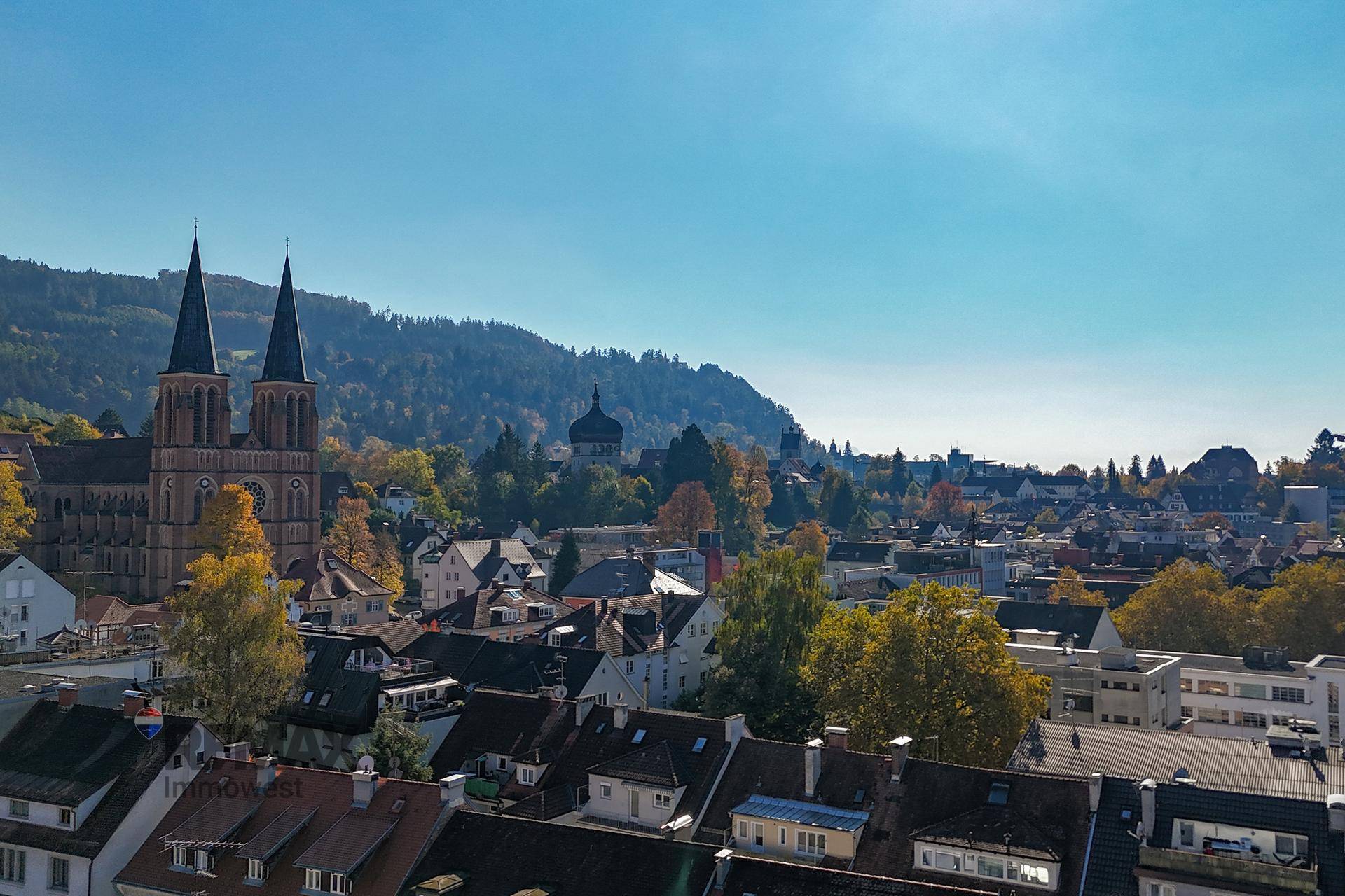 Panoramablick über die Stadt mit Kirchen, bewaldeten Hügeln und weitem Horizont.