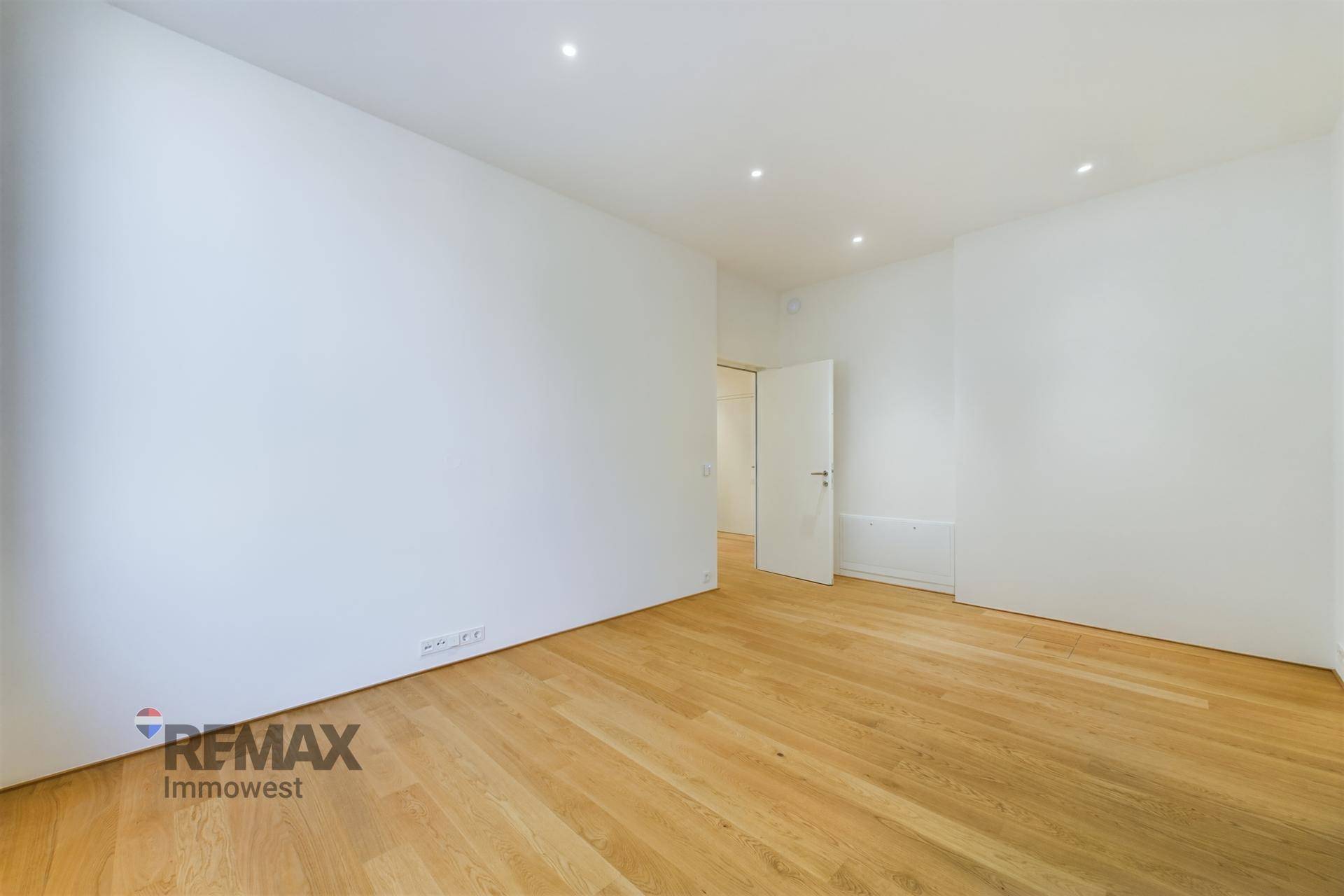 Helles Zimmer mit Holzboden und weiß gestrichenen Wänden, bereit zur individuellen Gestaltung.