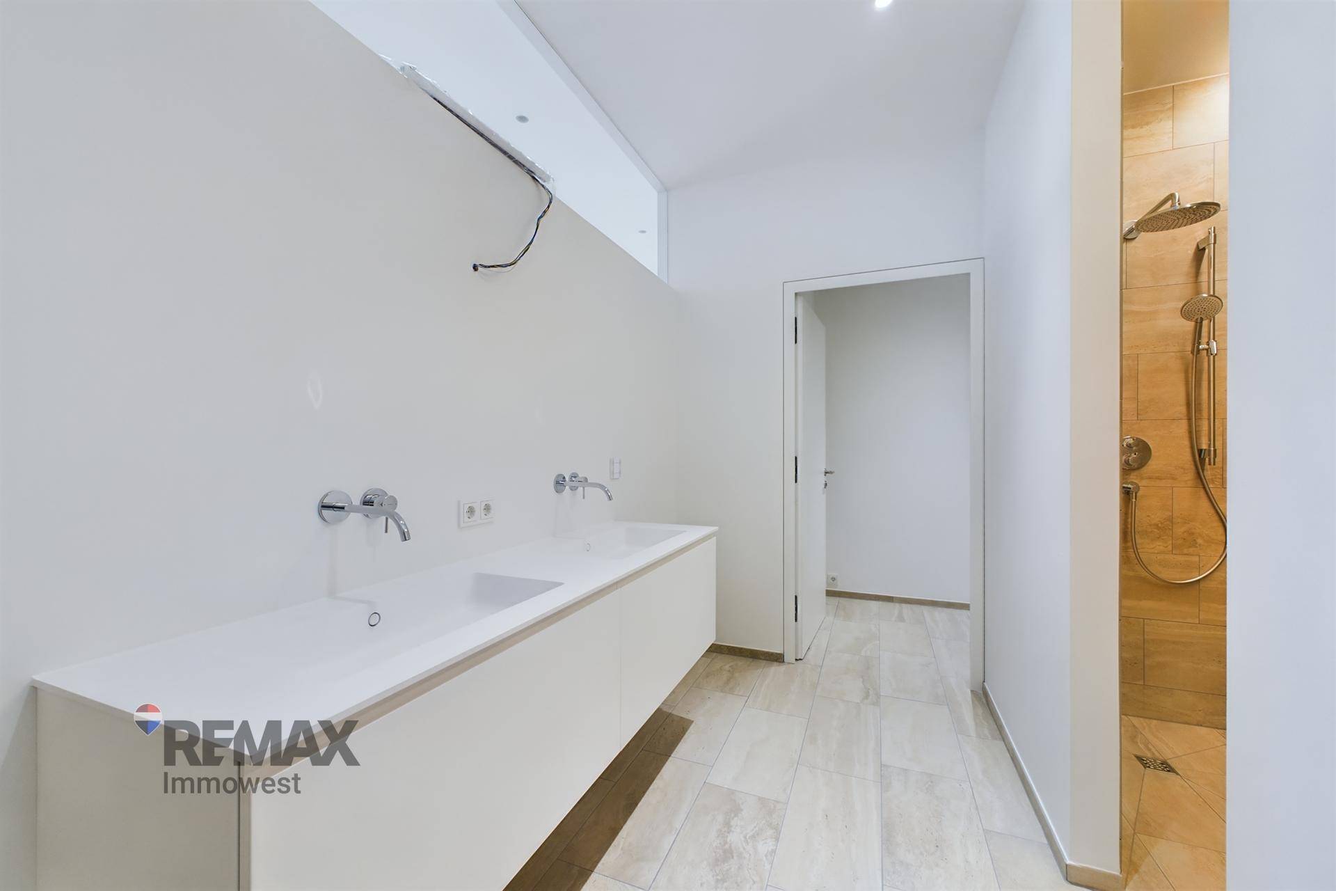 Modernes Badezimmer mit Doppelwaschbecken, begehbarer Dusche und hellen Fliesen.