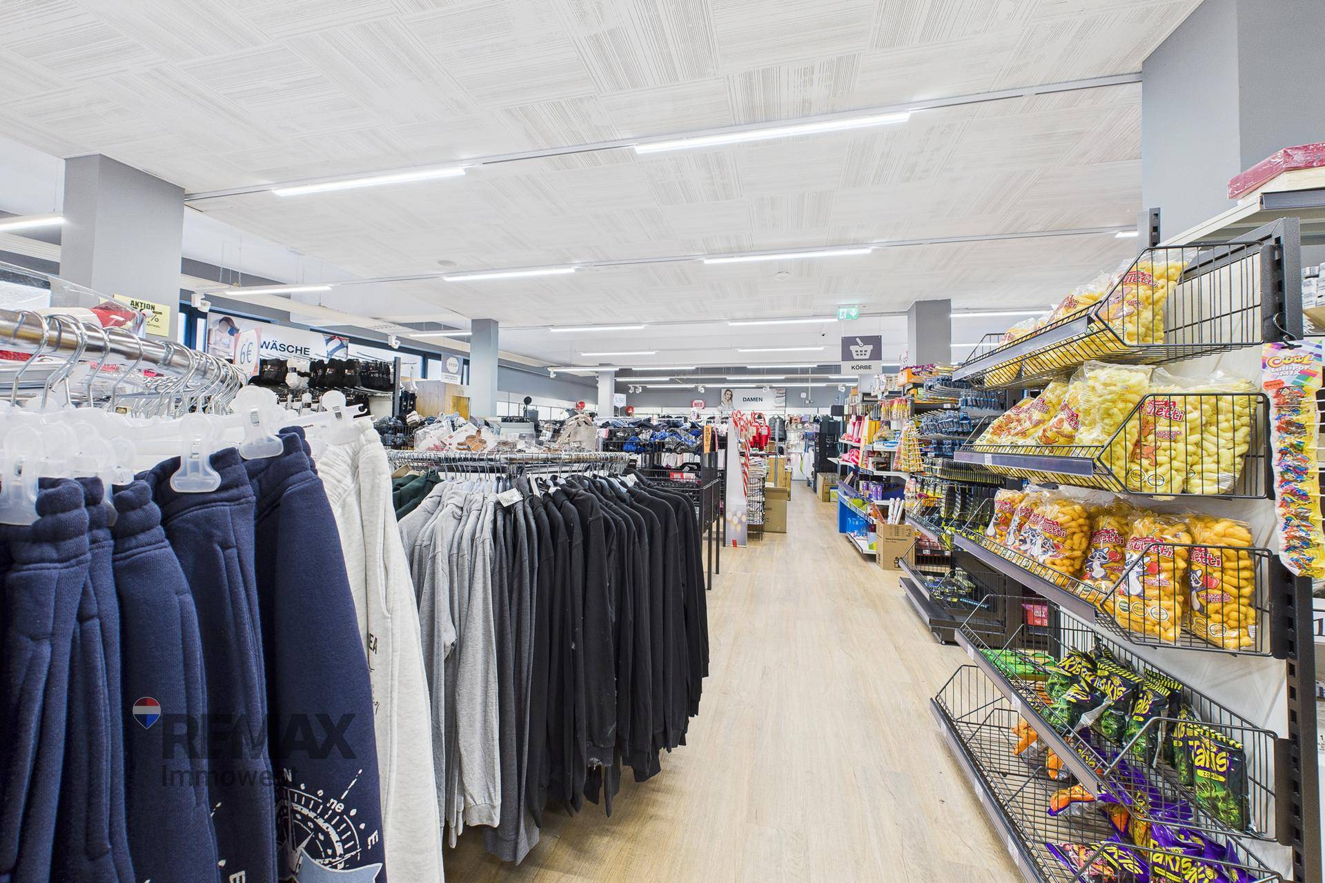 Geräumiger Verkaufsbereich mit Kleiderständern und Regalen, die eine Vielzahl von Produkten präsentieren.