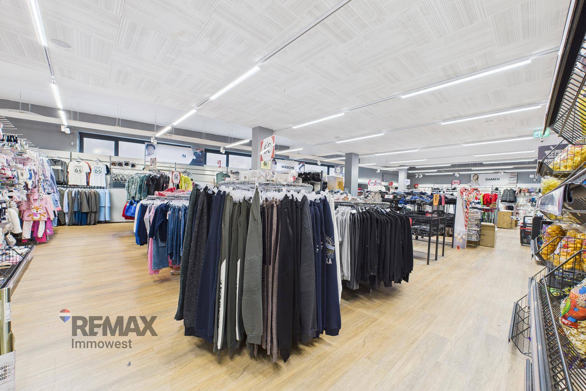 Weitläufiger Verkaufsraum mit zahlreichen Kleiderständern und Produktpräsentationen in hellem Ambiente.