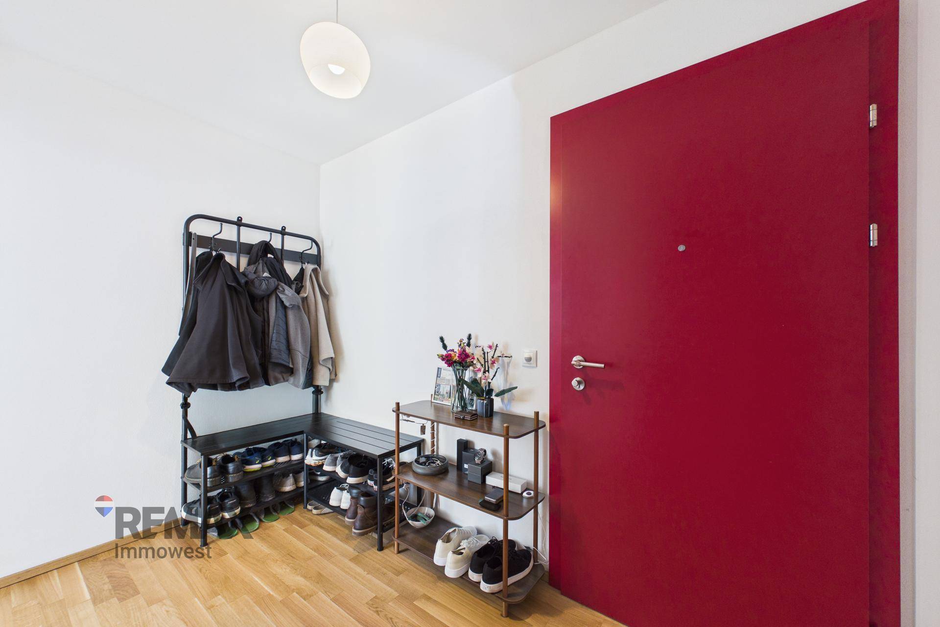 Eingangsbereich mit roter Tür, Holzfußboden und praktischer Garderobe.