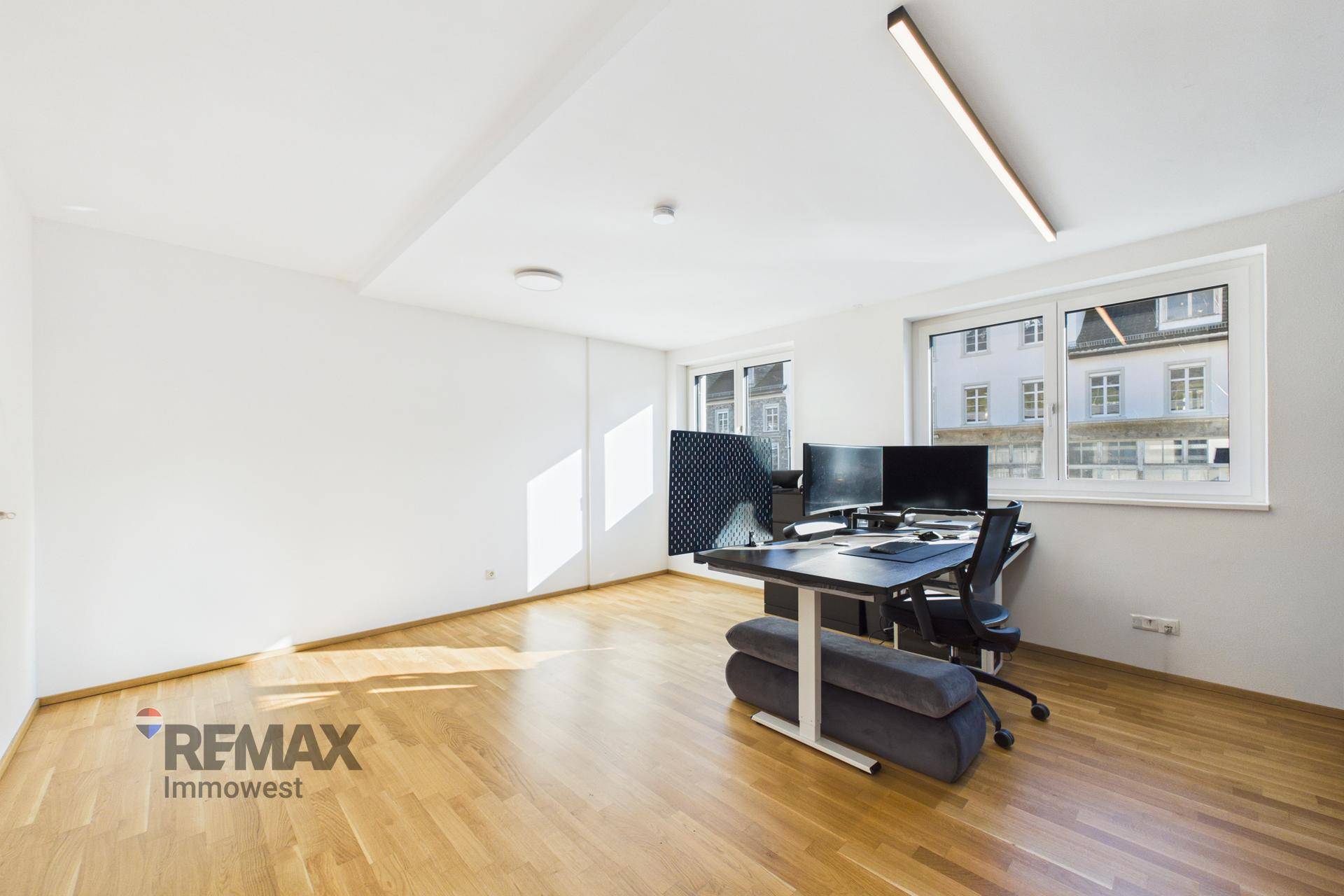 Großes Büro mit Holzfußboden, viel Tageslicht und Blick auf die Umgebung.