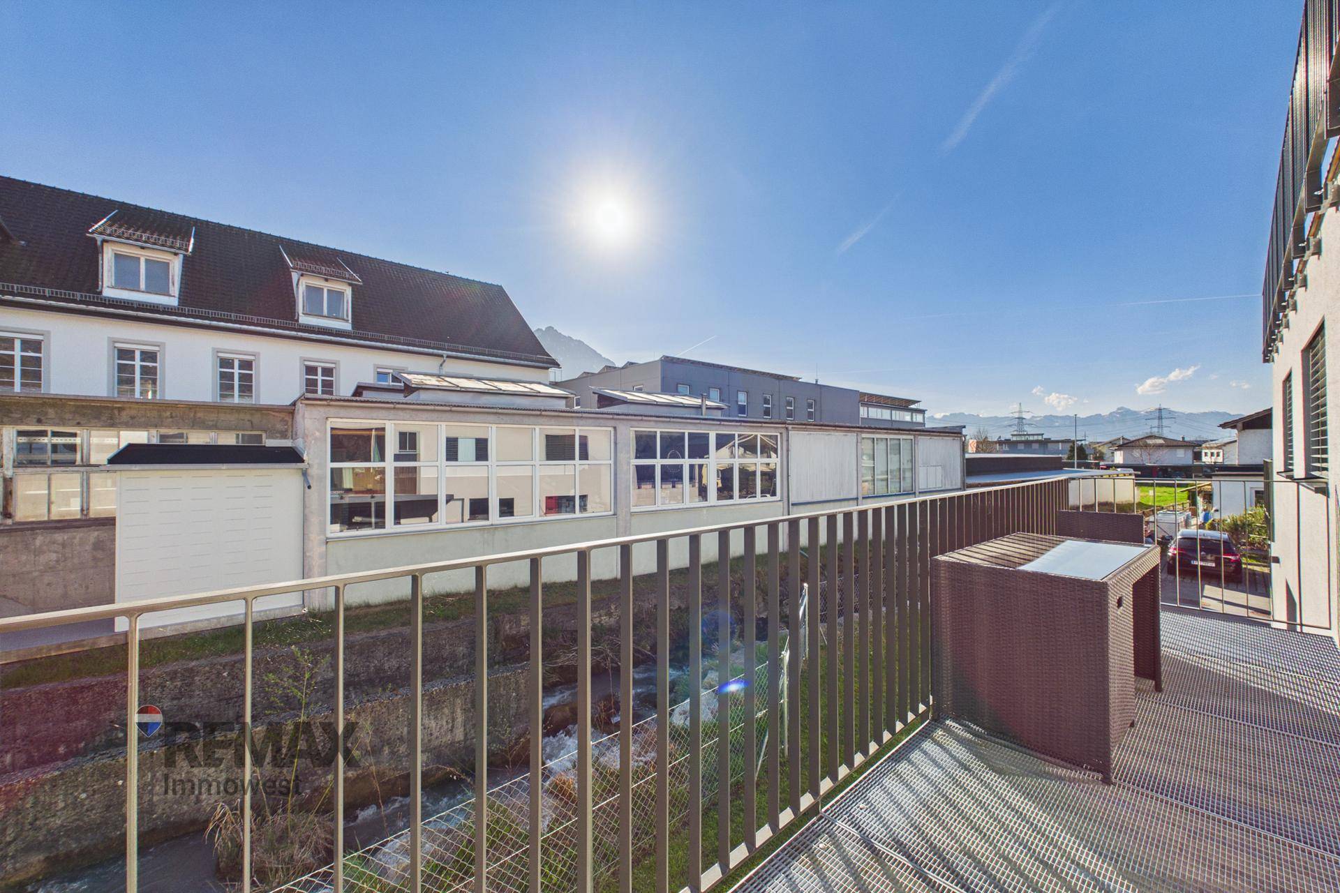 Heller Balkon mit Sitzmöbeln und weitem Blick über die Umgebung und Berge.
