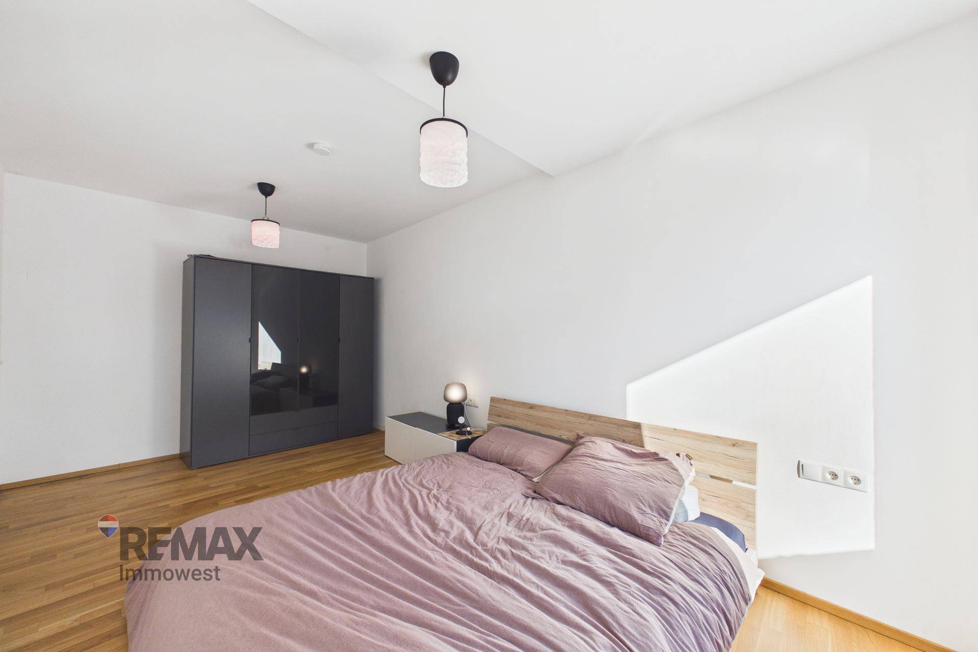 Gemütliches Schlafzimmer mit Doppelbett, Kleiderschrank und Holzfußboden.