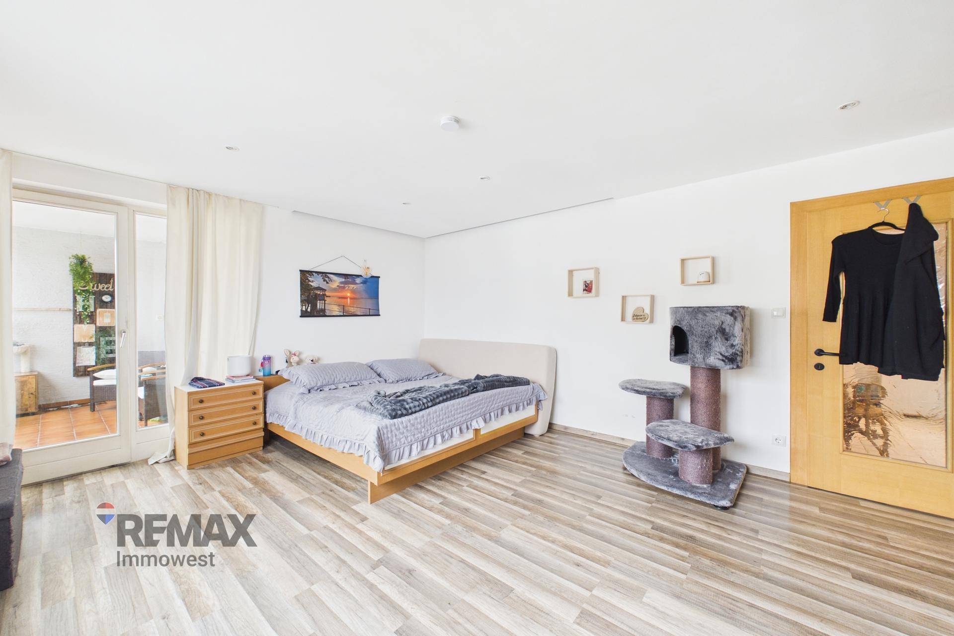 Helles Schlafzimmer mit Balkonzugang durch eine Glastür und schlichtem, modernem Mobiliar.