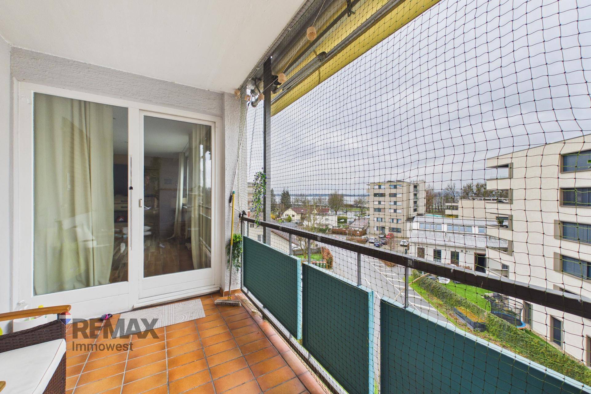 Geräumiger Balkon mit Terrakottafliesen und Sicherheitsnetz, bietet einen weiten Blick über die Stadt.