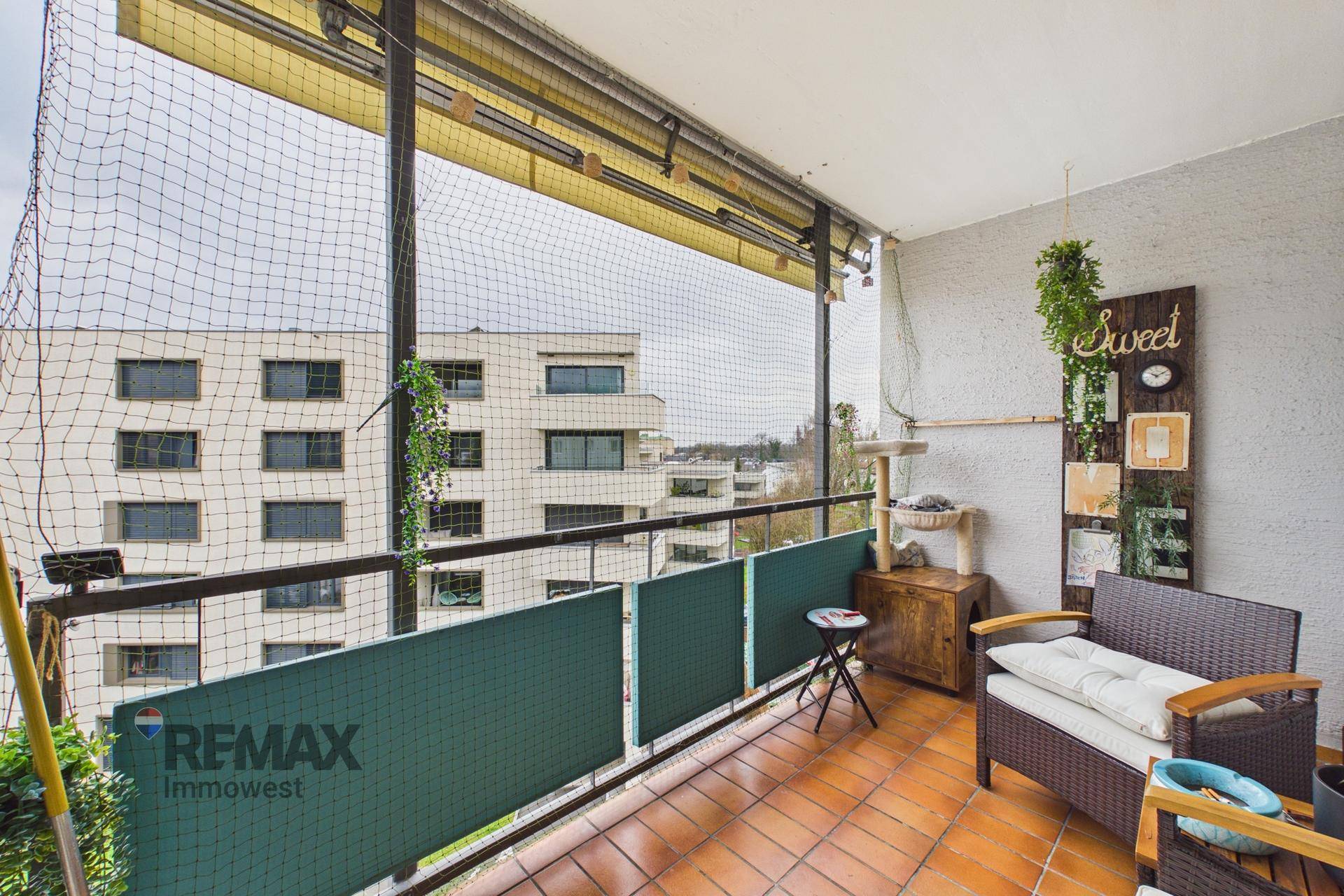 Balkon mit Terrakottafliesen, Sitzgelegenheiten und einem Sicherheitsnetz mit Blick auf die Umgebung.