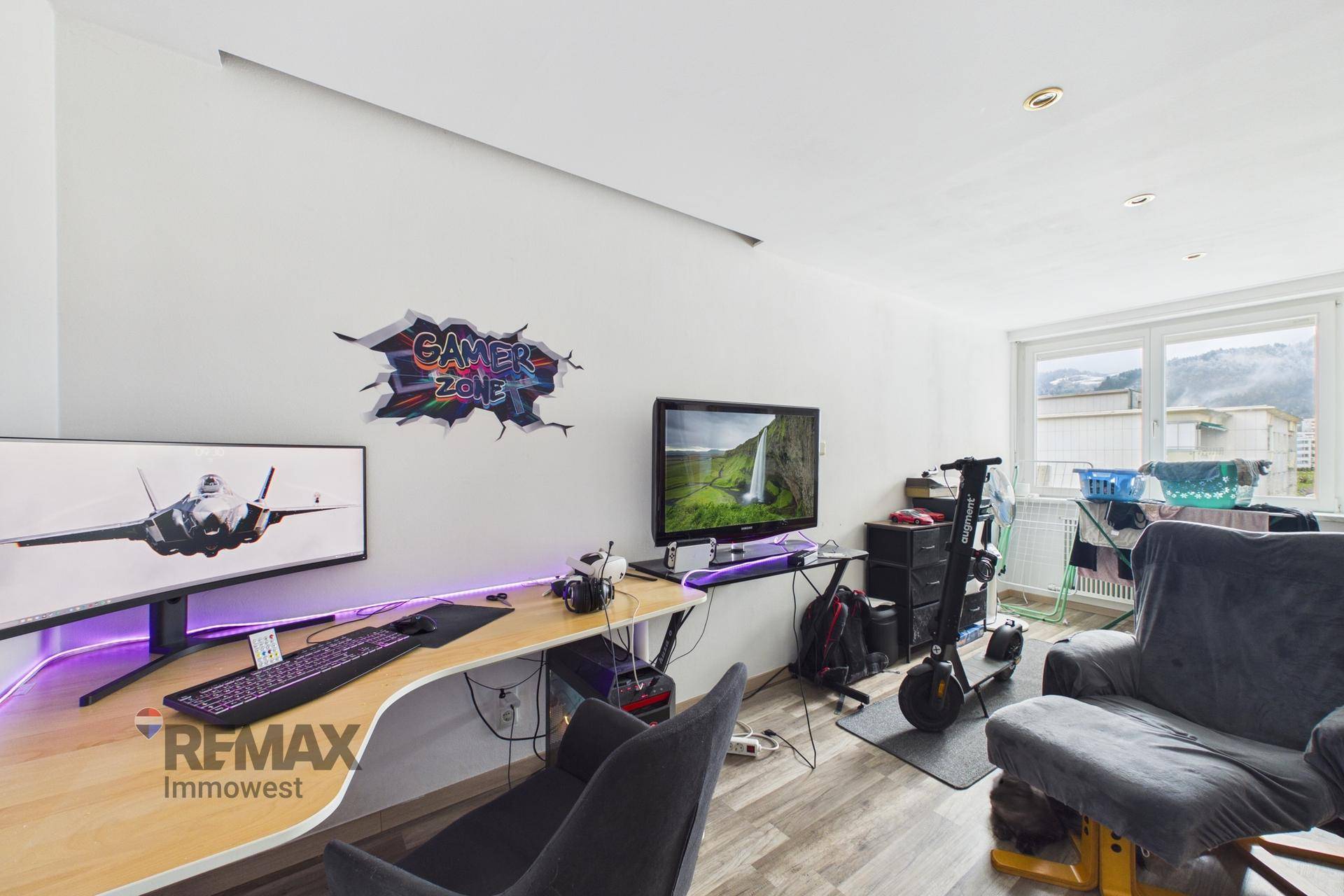 Modernes Büro- und Gaming-Zimmer mit Schreibtisch, Computerausstattung und Fensterblick.