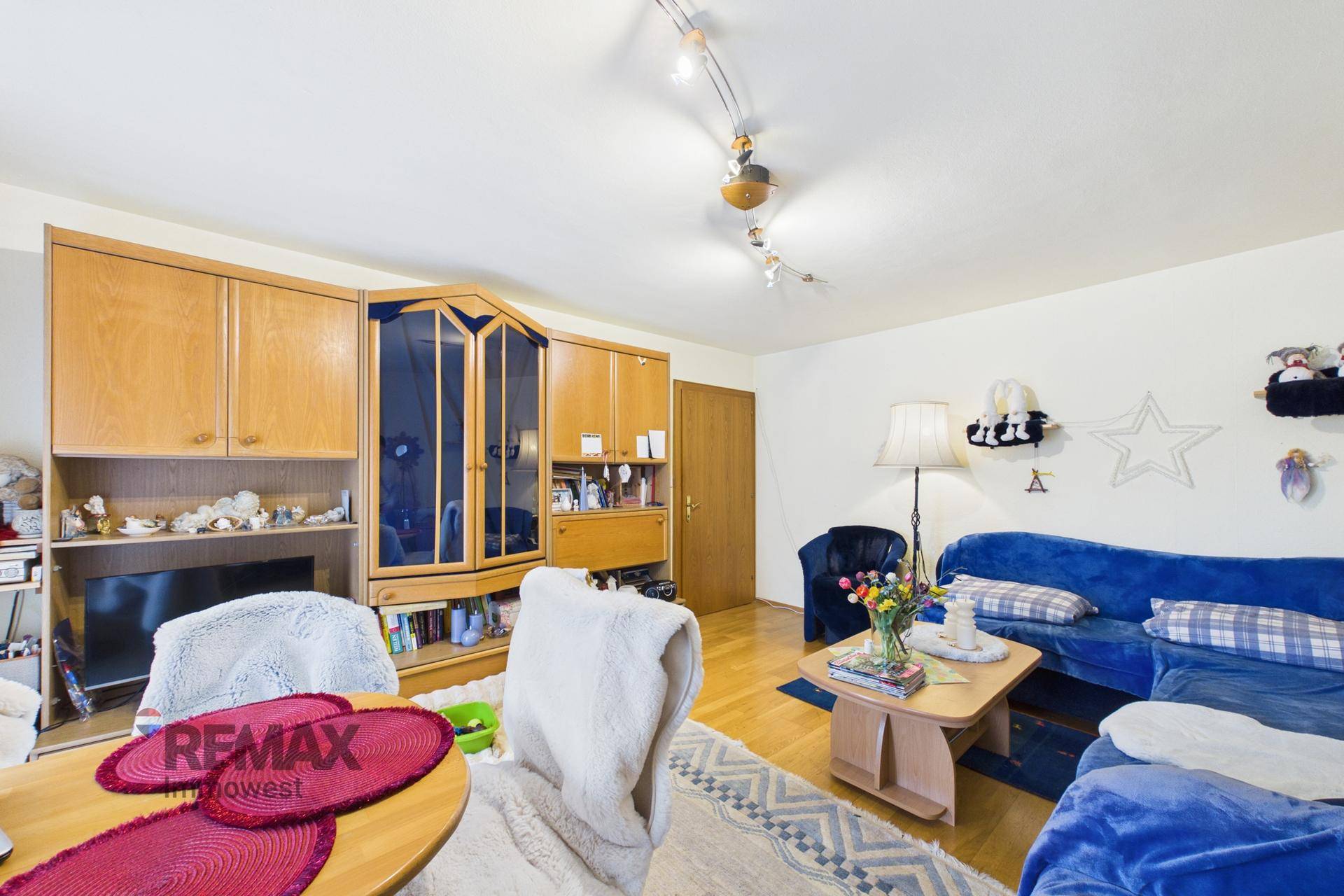 Wohnzimmer mit traditionellen Holzmöbeln, blauer Couch und einem Essbereich.