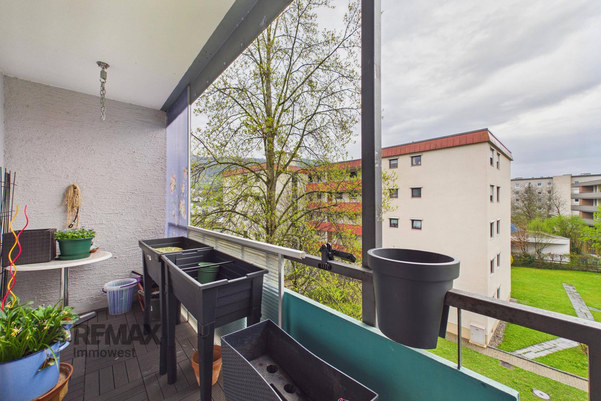 Balkon mit Blick auf die umliegende Wohngegend und grüne Bäume, ausgestattet mit Pflanzen.