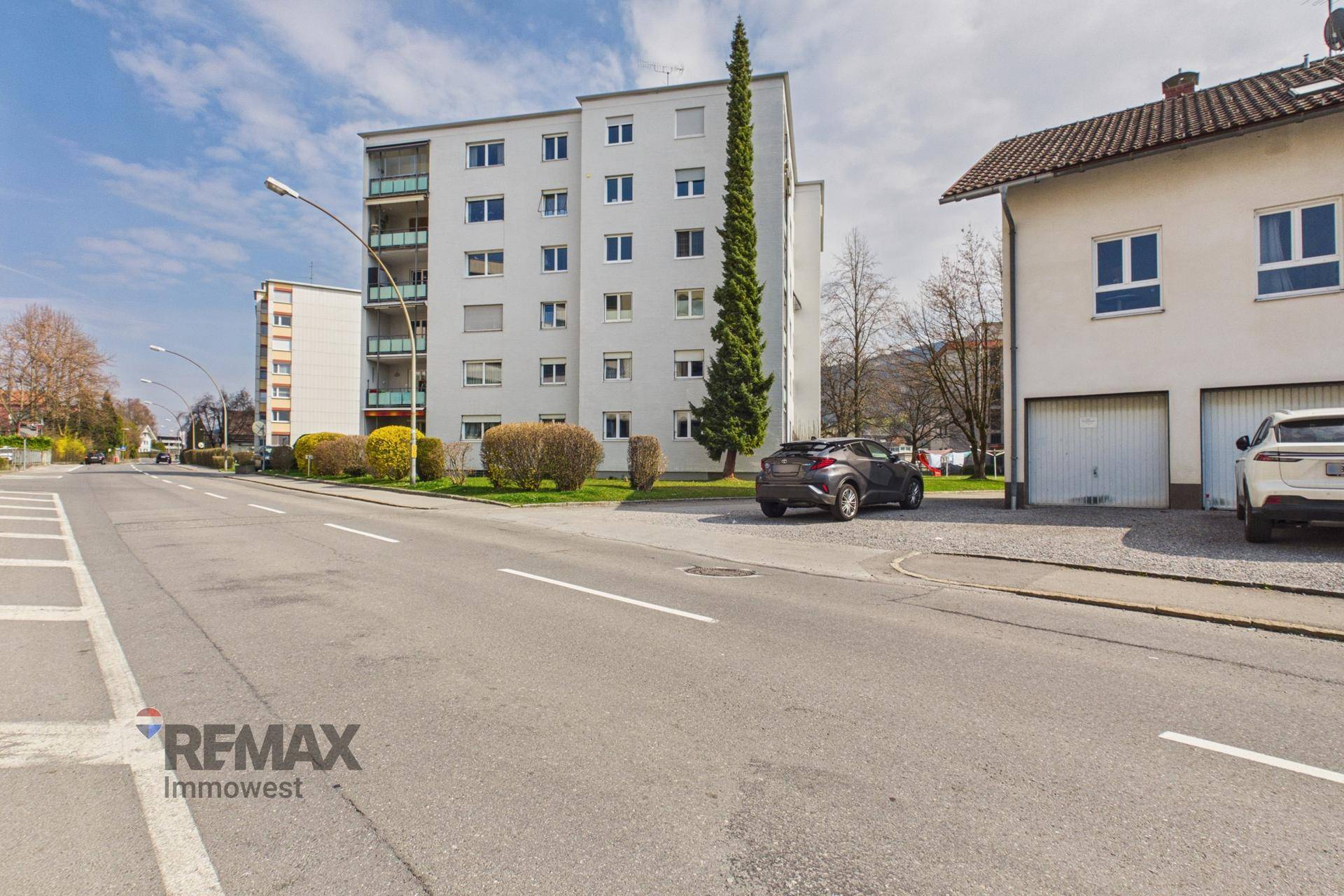 Mehrfamilienhaus mit weißer Fassade und Balkonen, gelegen an einer ruhigen Straße.