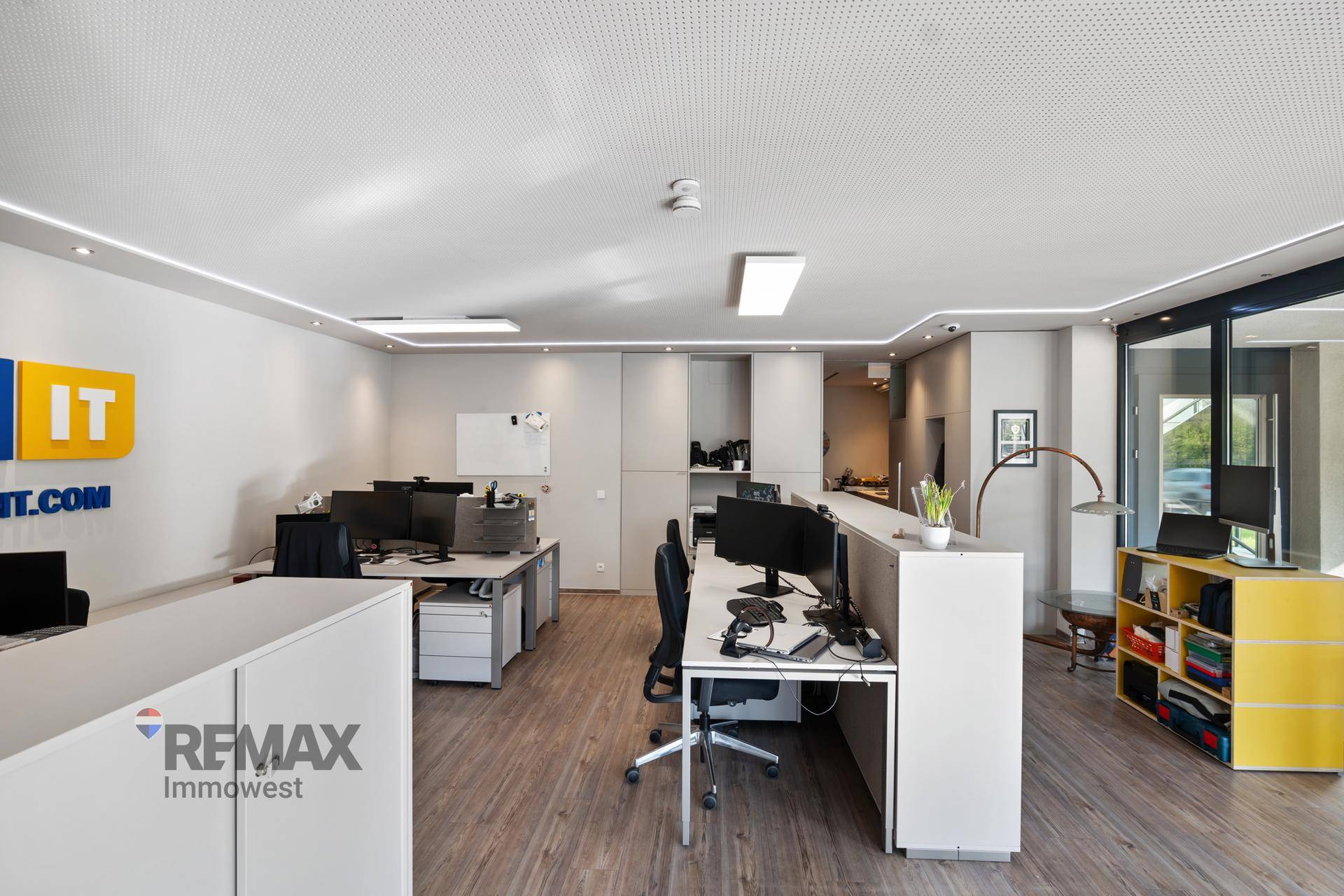 Geräumiges Büro mit mehreren Schreibtischen, ergonomischen Stühlen und einem modernen Beleuchtungssystem.