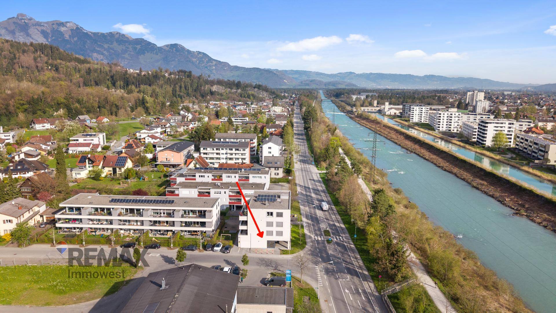 Weitläufige Luftaufnahme eines Gebäudes an einem Fluss mit umliegender Wohn- und Gewerbebebauung.