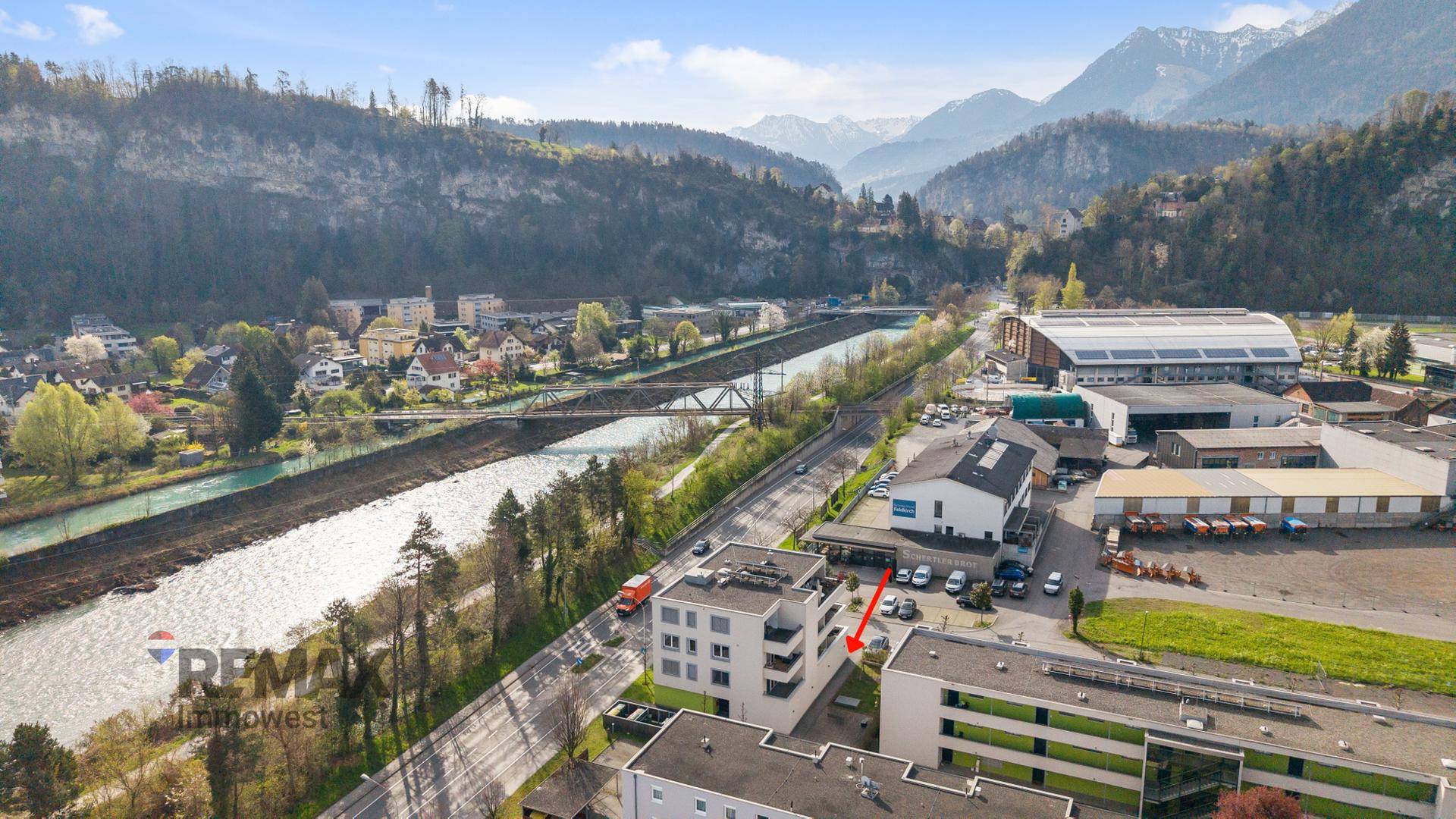 Panoramablick aus der Vogelperspektive auf das Gebäude, den Fluss und die beeindruckende Berglandschaft.