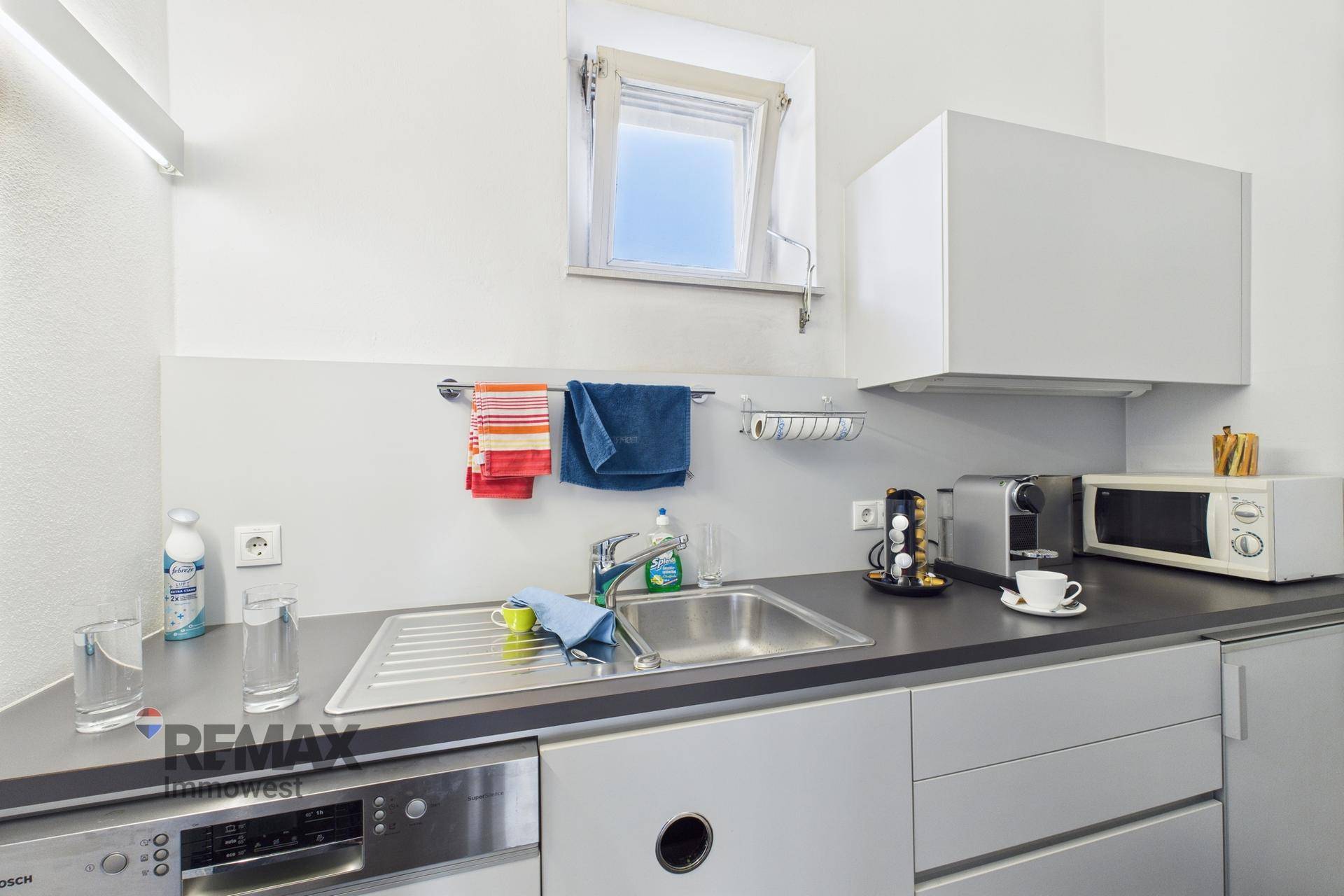 Detailansicht der Küchenzeile mit Spülbecken, Spülmaschine und Kaffeemaschine.