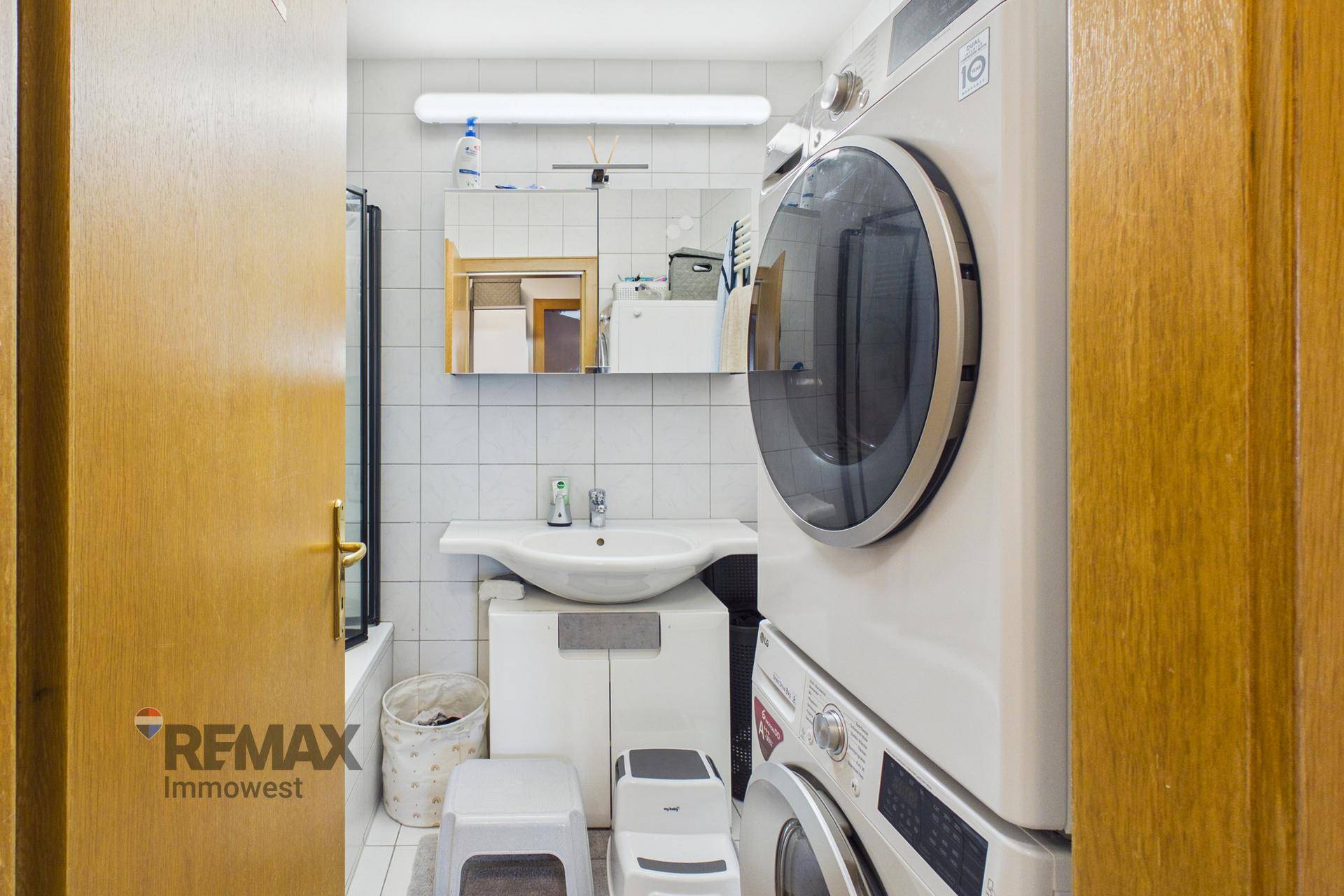 Funktionales Badezimmer mit Waschbecken, Badewanne und integrierter Waschmaschine.