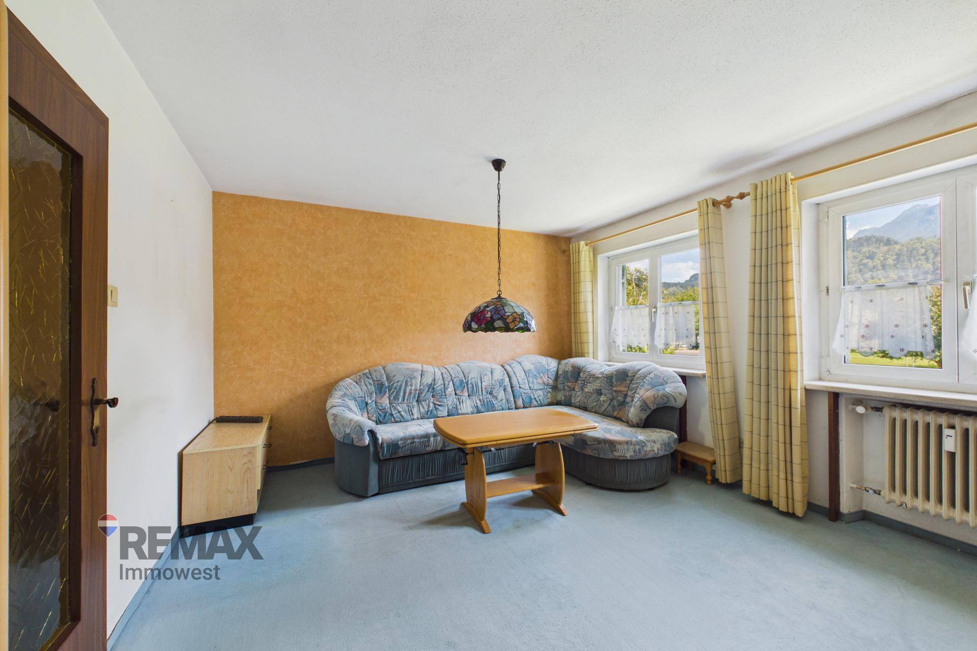 Wohnzimmer mit gemütlichem Sofa, Teppichboden und Fenstern, die einen Bergblick bieten.