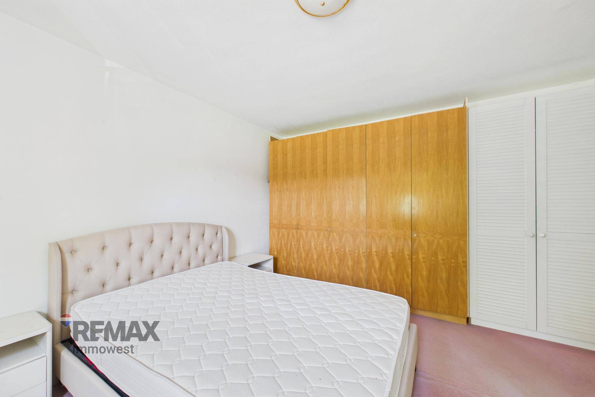 Schlafzimmer mit großem Doppelbett und geräumigen Holzschränken für ausreichend Stauraum.