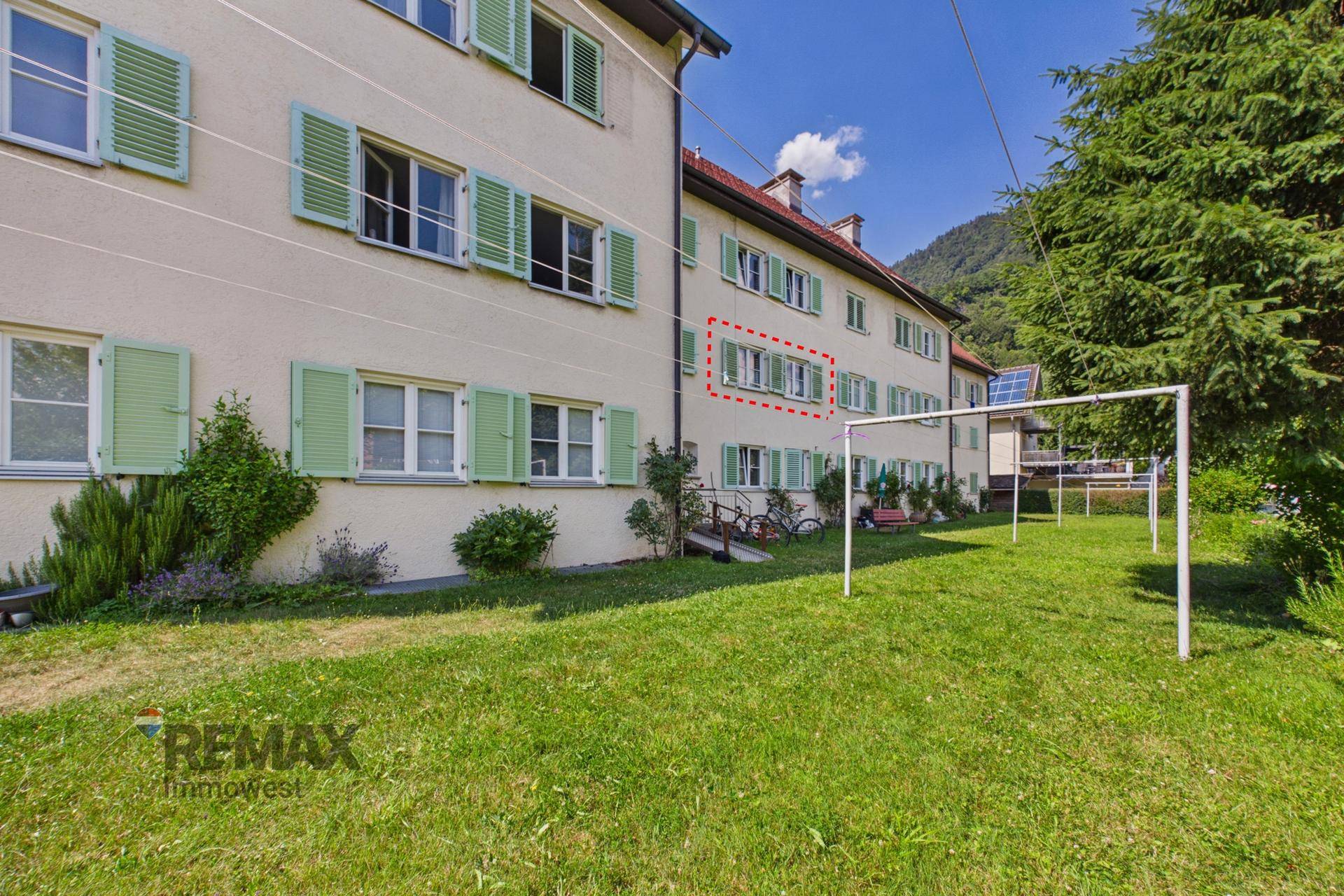 Gemeinschaftsgarten mit Rasenfläche und Wäscheständern hinter dem Wohngebäude.