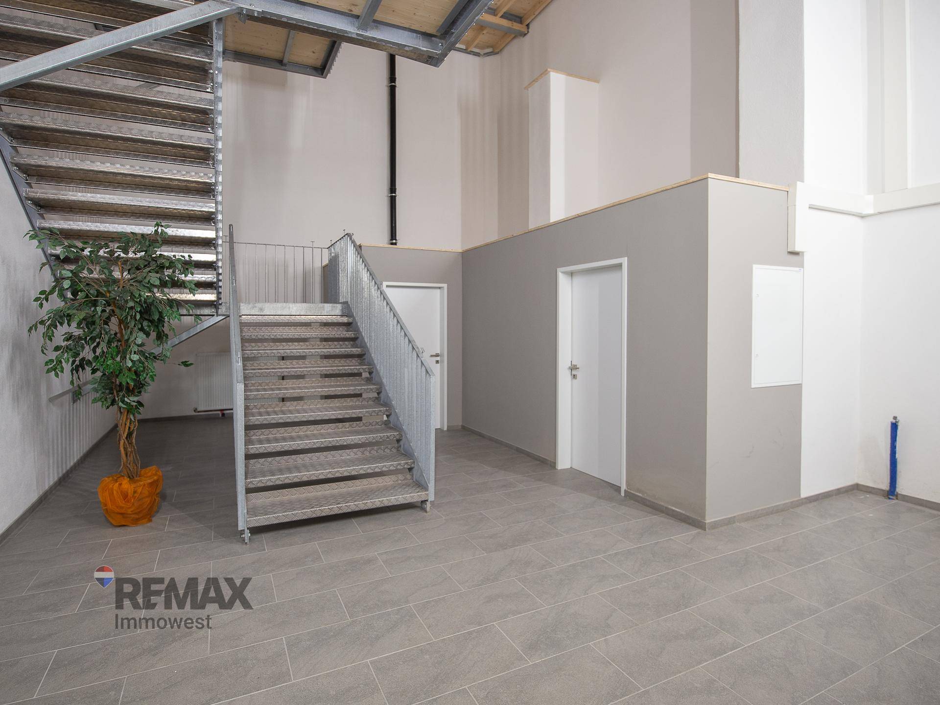 Geräumiger Flurbereich mit einer robusten Metalltreppe und mehreren Türen, die zu weiteren Räumen führen.