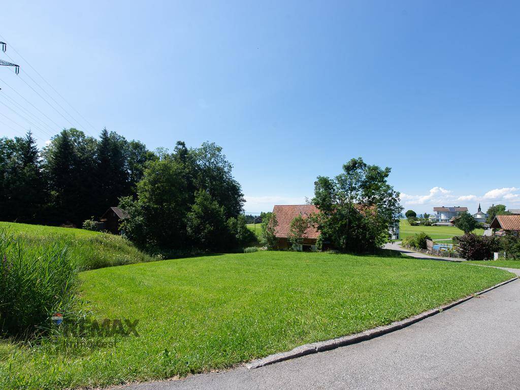 Idyllische ländliche Umgebung mit weiten Grünflächen und einem traditionellen Haus in der Ferne.