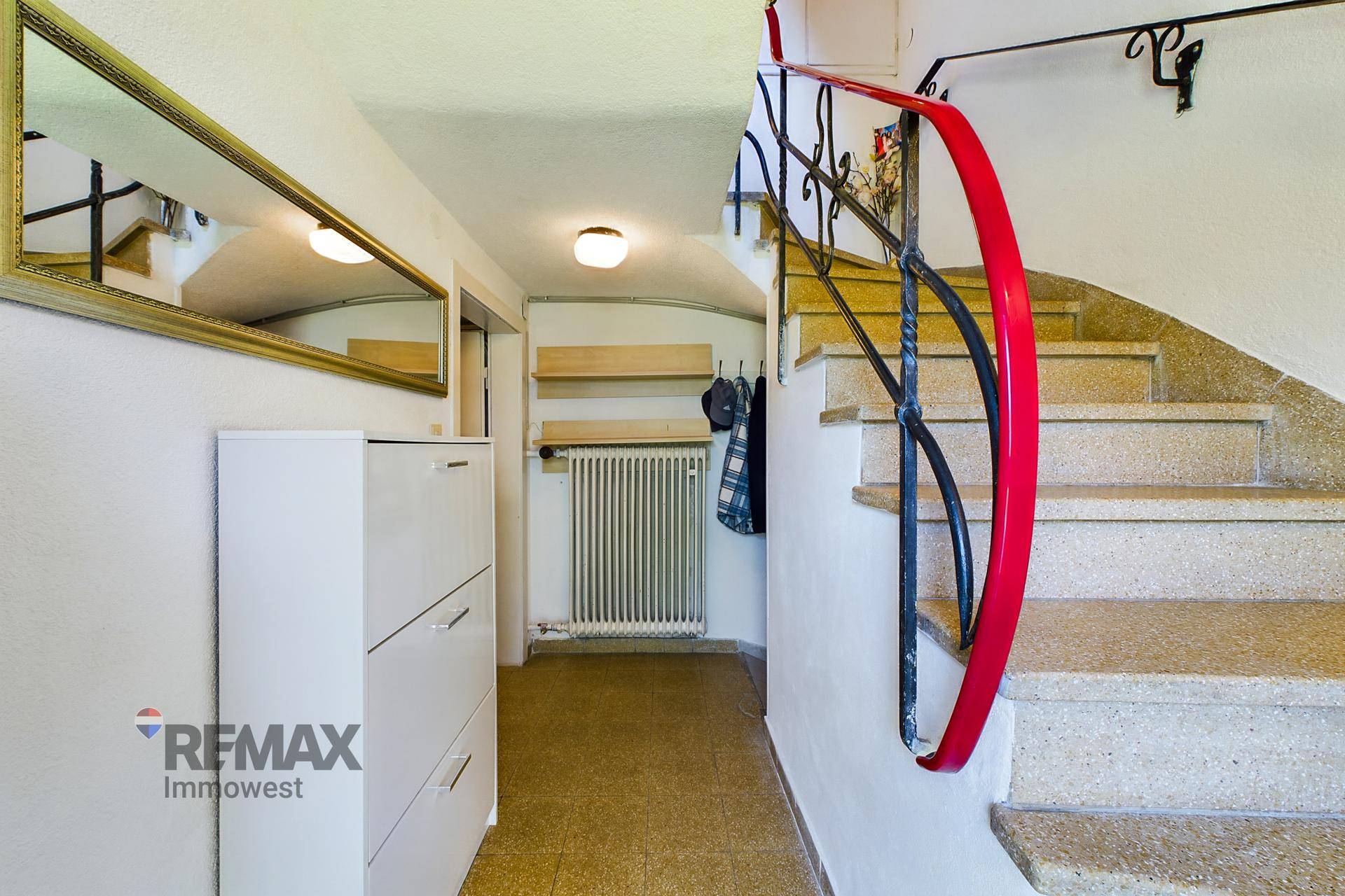 Eingangsbereich mit Steintreppe, Spiegel und Schuhschrank, der in die obere Etage führt.