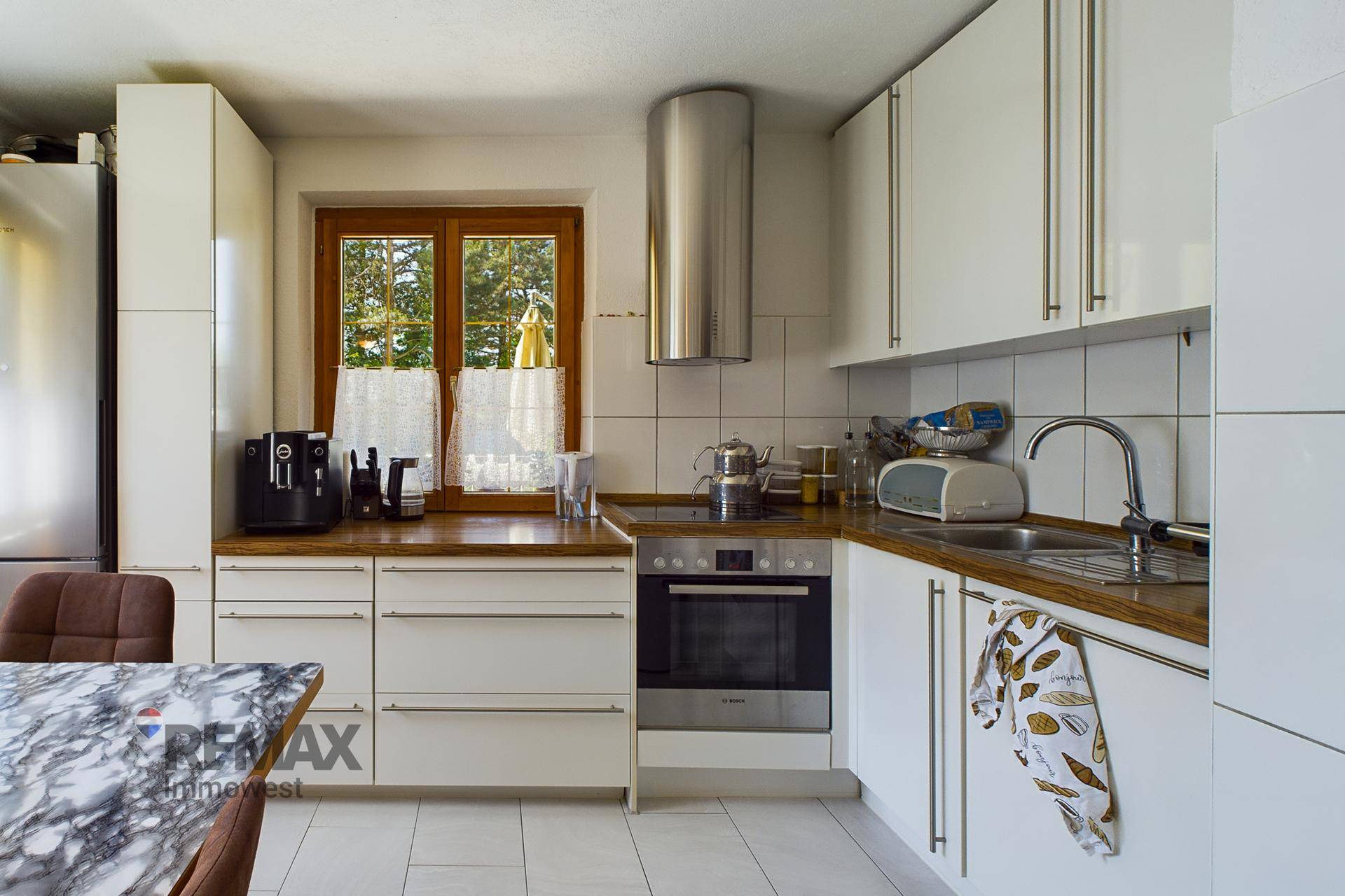 Helle Küche mit weißen Schränken, Holzarbeitsplatte und modernen Geräten, inklusive Backofen.