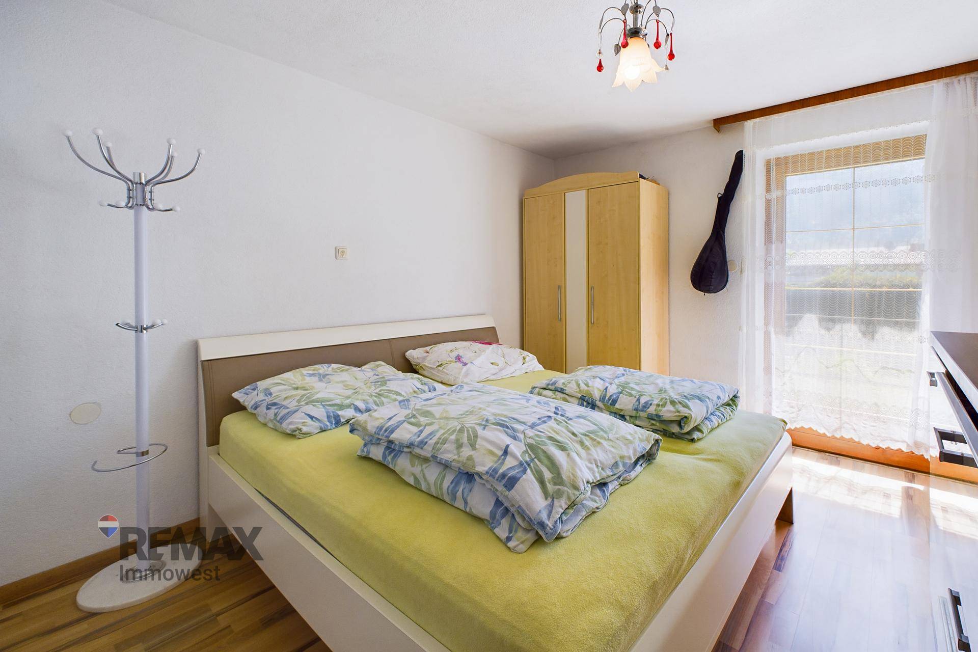 Schlafzimmer mit Doppelbett, Kleiderschrank und Zugang zu einem Balkon oder einer Terrasse.