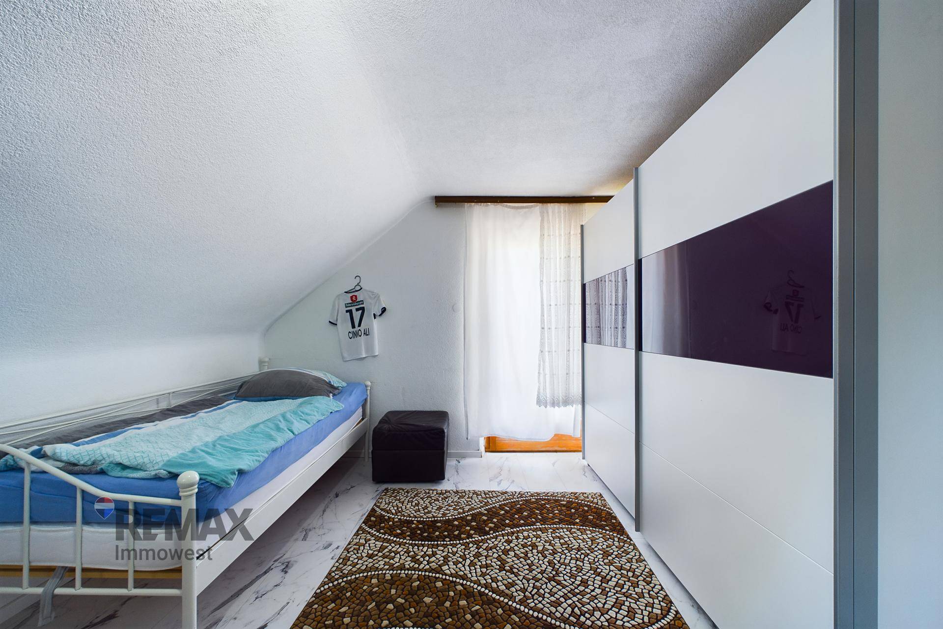 Helles Dachzimmer mit Einzelbett, Schiebetürenschrank und Fenster, ideal für Kinder oder Gäste.