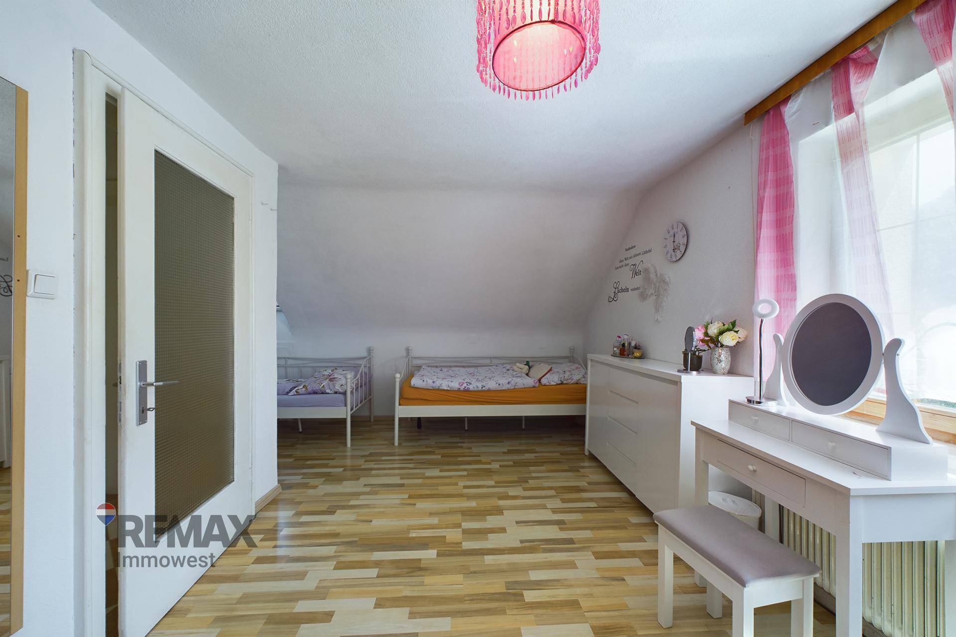 Dachzimmer mit zwei Einzelbetten, Schminktisch und Holzboden, unter einer Dachschräge gelegen.