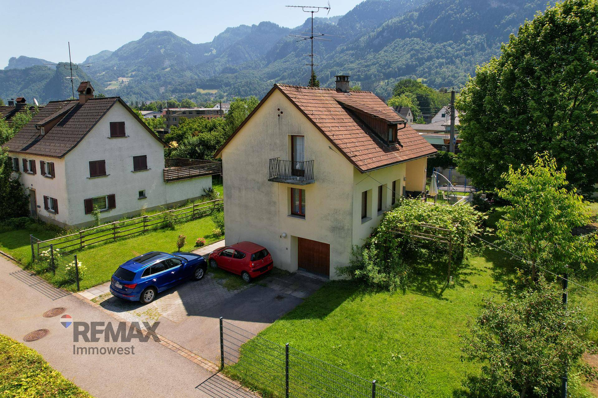 Vorderansicht des Einfamilienhauses mit Garage, Stellplätzen und Balkon im Obergeschoss.