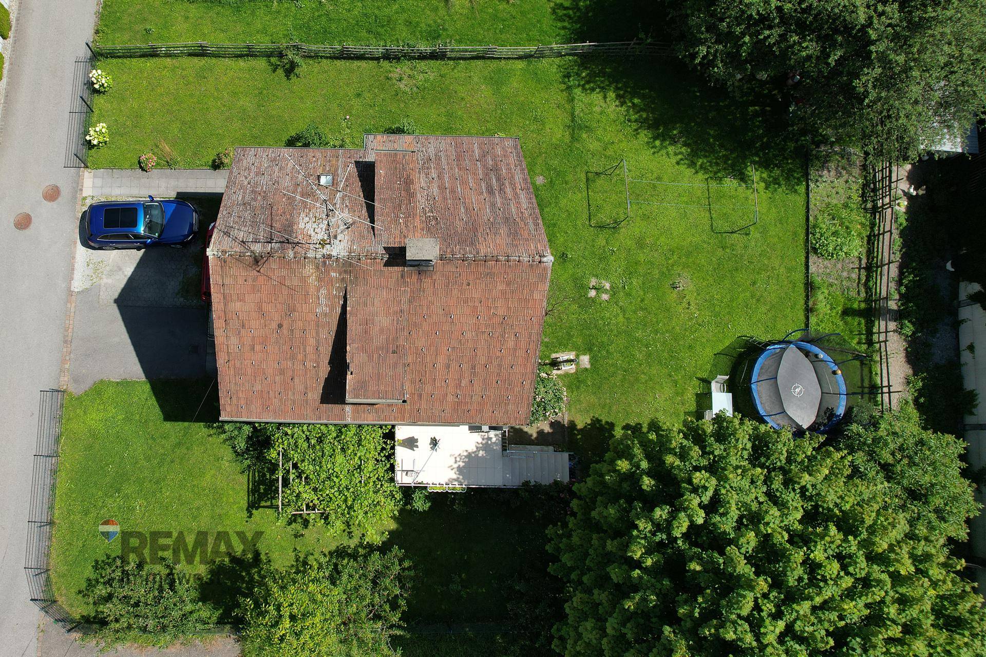 Luftaufnahme des Hauses mit Garten, Trampolin und umliegender Grünfläche.