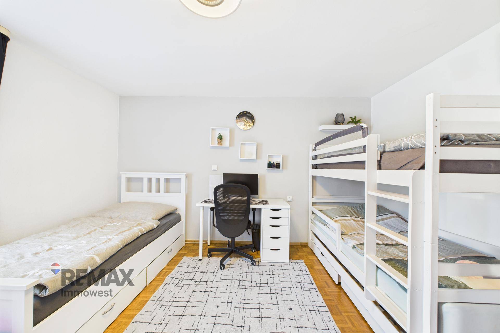 Kinderzimmer mit Einzelbett, Etagenbett und Schreibtisch für mehrere Kinder.