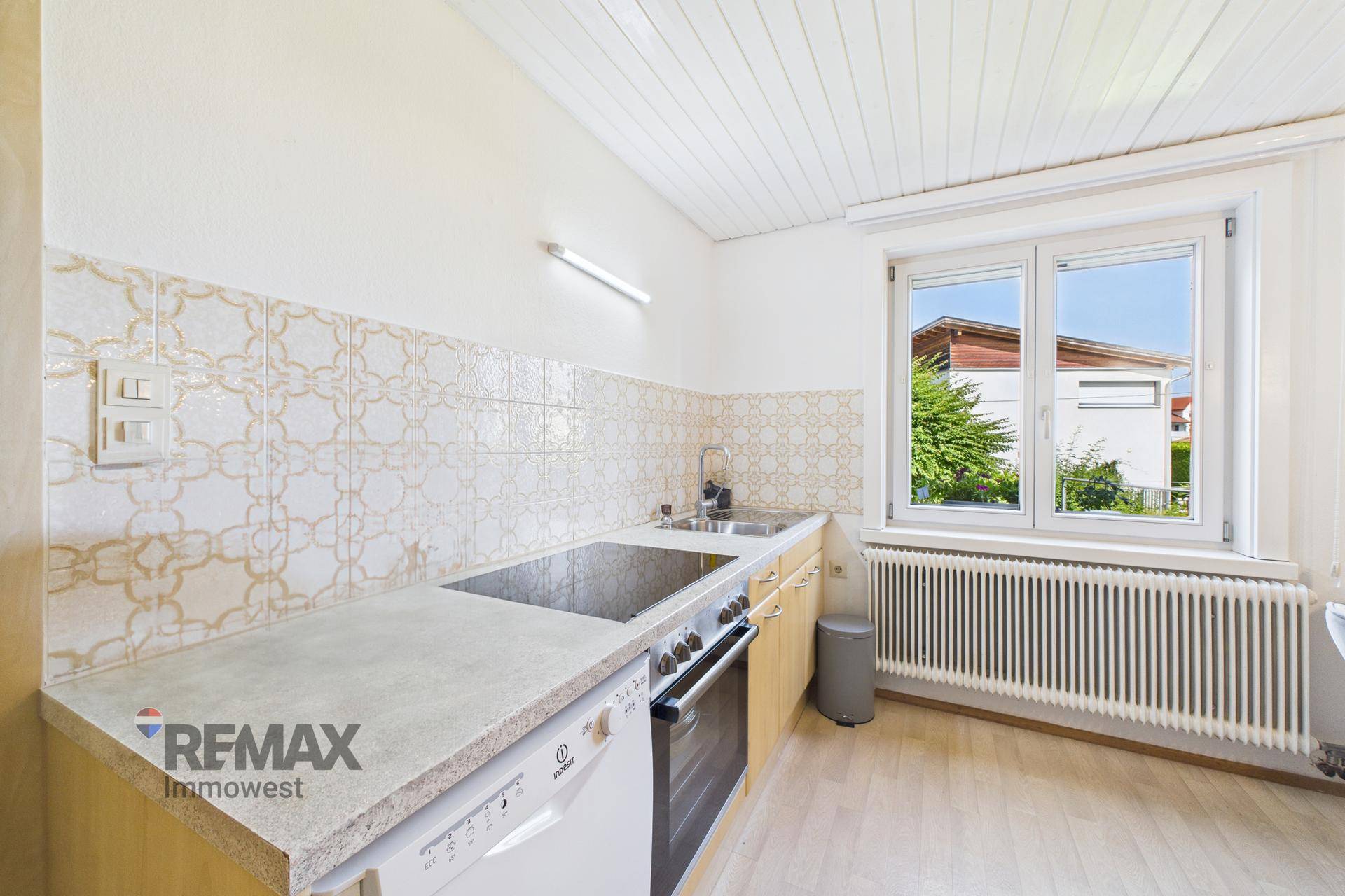 Funktionale Küche mit Einbaugeräten, Arbeitsplatte und Fensterblick ins Grüne.