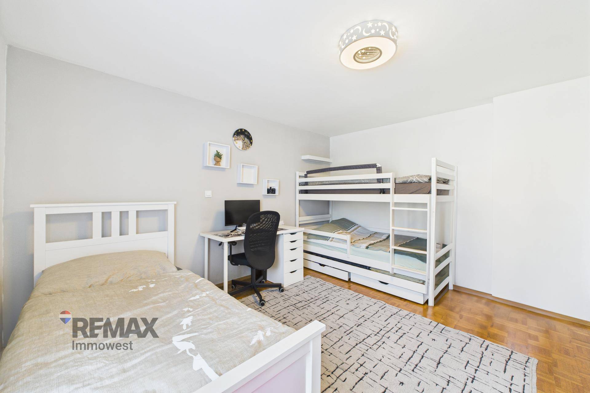 Geräumiges Kinderzimmer mit Einzelbett, Etagenbett und Arbeitsbereich.