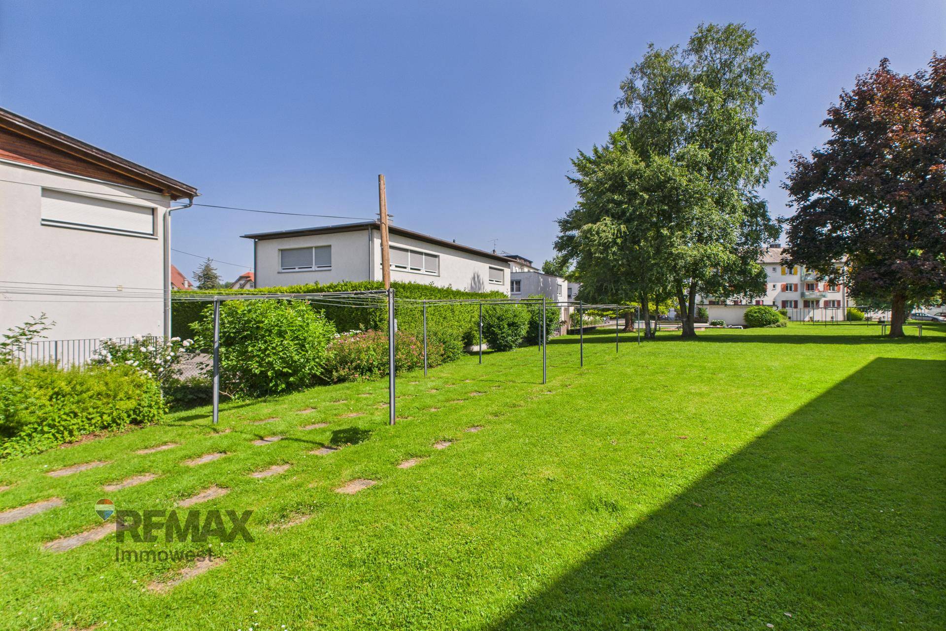 Große, gepflegte Rasenfläche mit Wäscheleinen und Bäumen im Gemeinschaftsgarten.