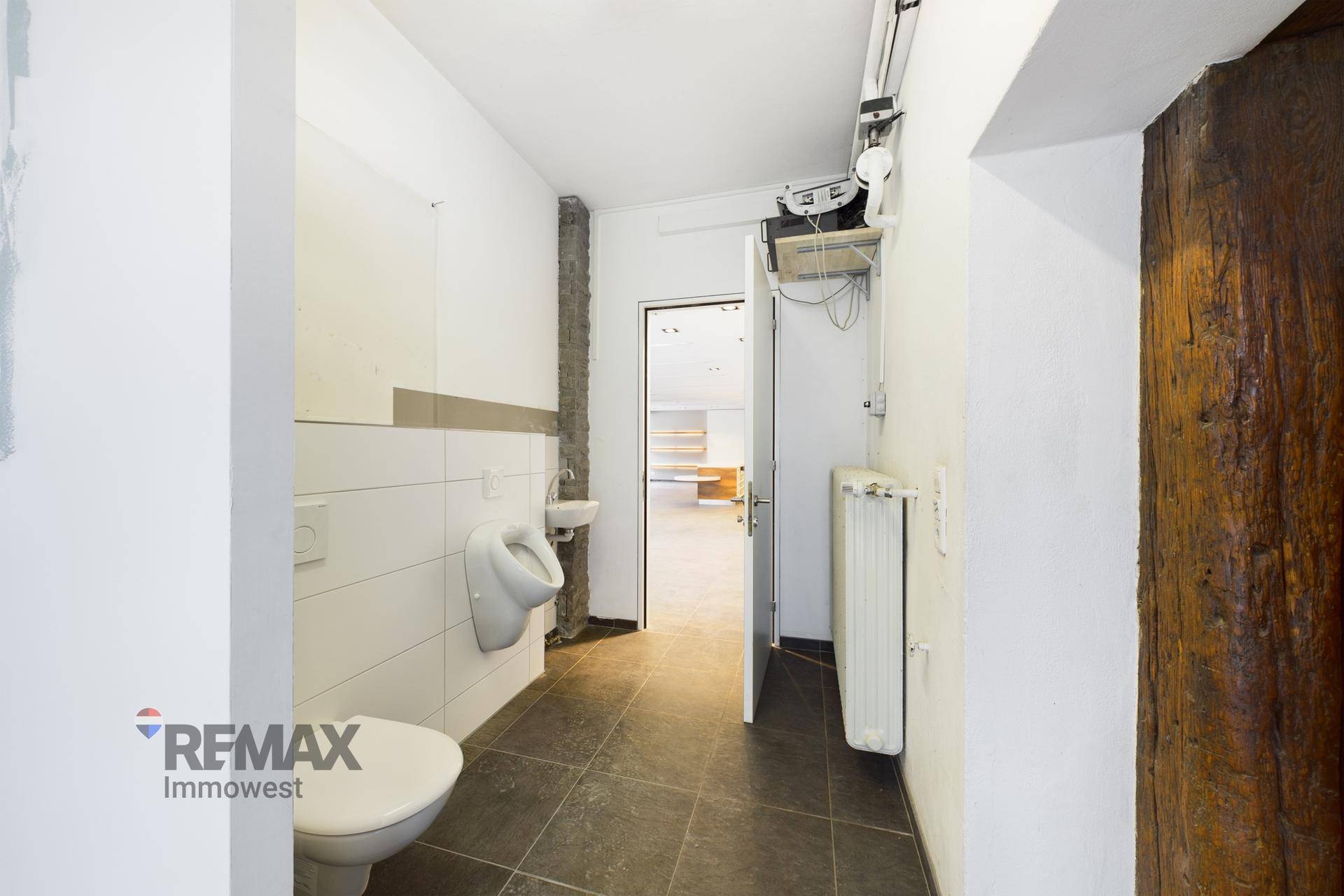 Gästetoilette mit Urinal, WC und Heizkörper, gut beleuchtet.