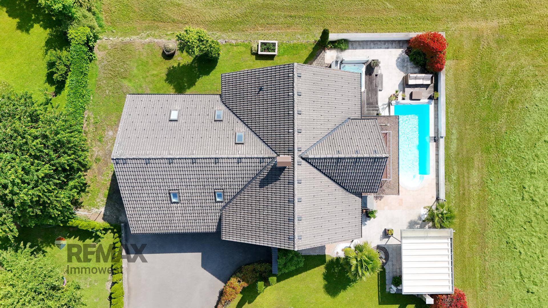 Dachansicht des Hauses mit Satteldach, Dachfenstern und dem angrenzenden Poolbereich.