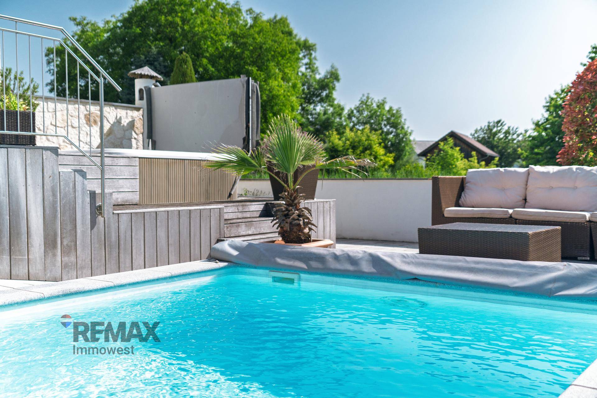 Poolbereich mit Holzdeck, bequemen Outdoor-Möbeln und integriertem Whirlpool.
