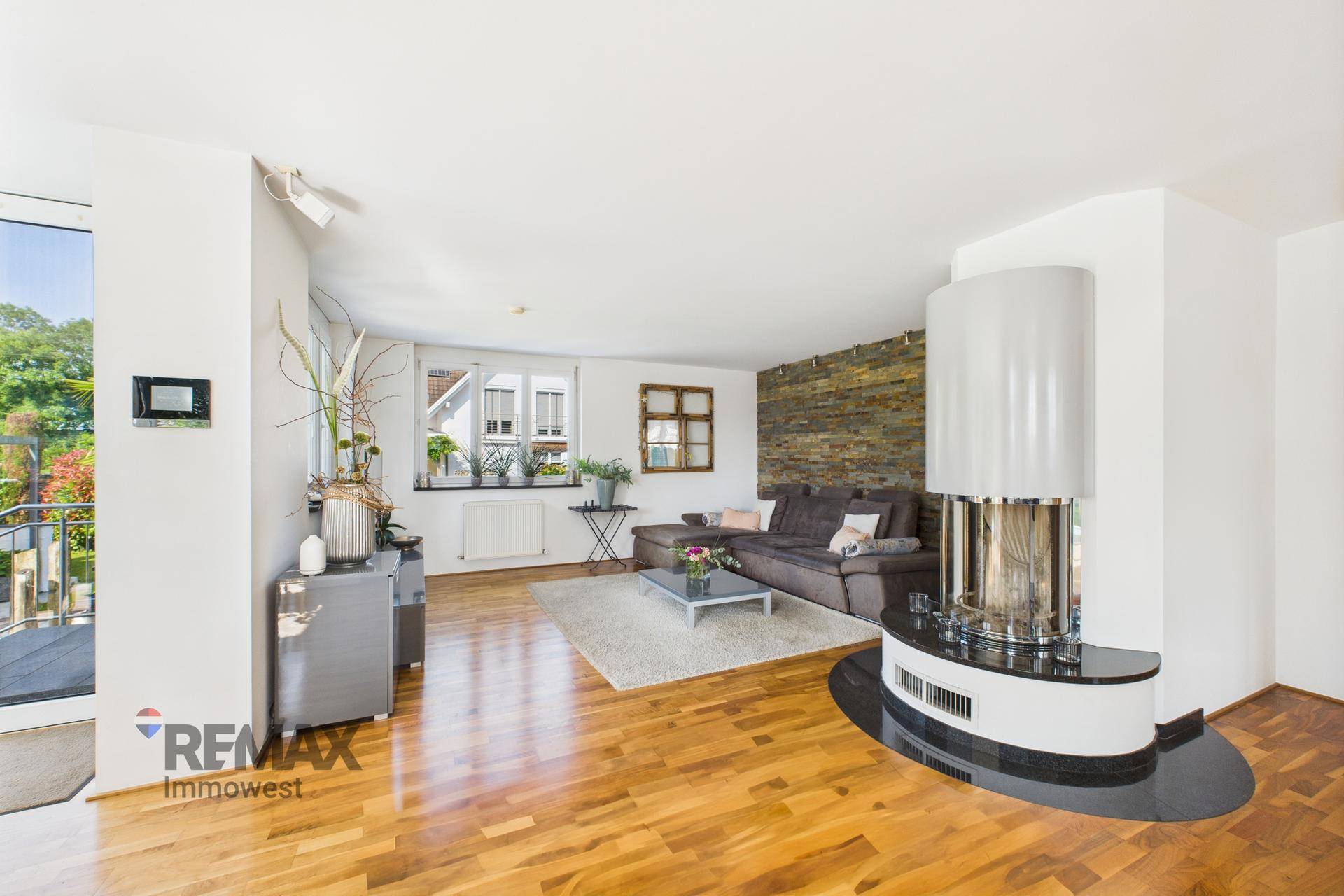 Gemütliches Wohnzimmer mit Sofa, Steinwandakzent und elegantem Kamin.