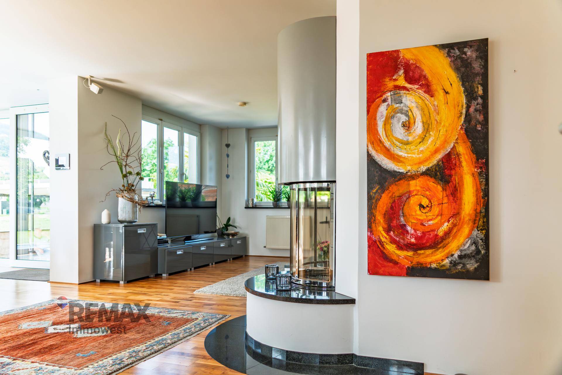 Helles Wohnzimmer mit modernem Kamin, Holzboden und farbenfrohem Kunstwerk.