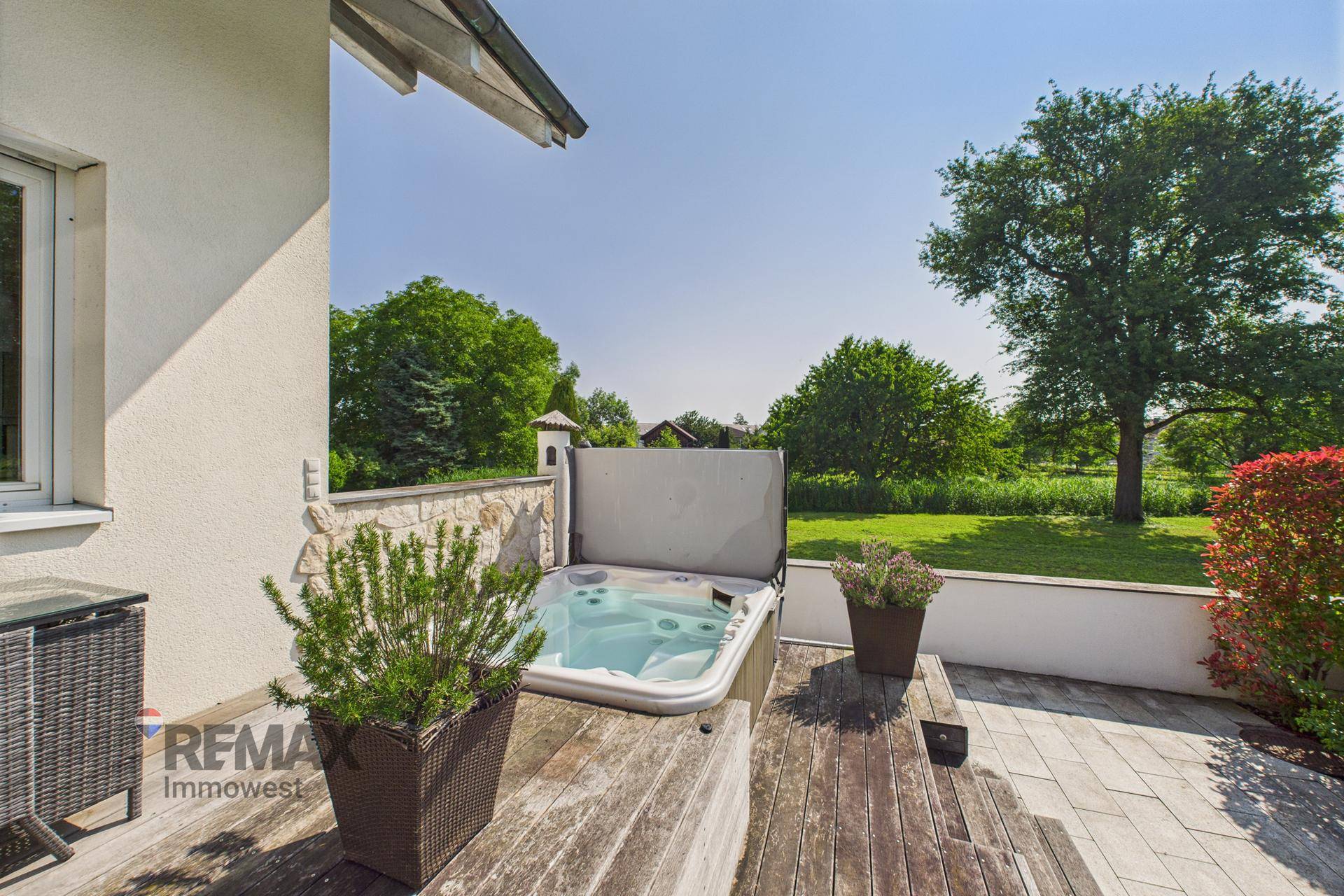 Whirlpool auf einer Holzterrasse mit weitem Blick in die grüne Landschaft.