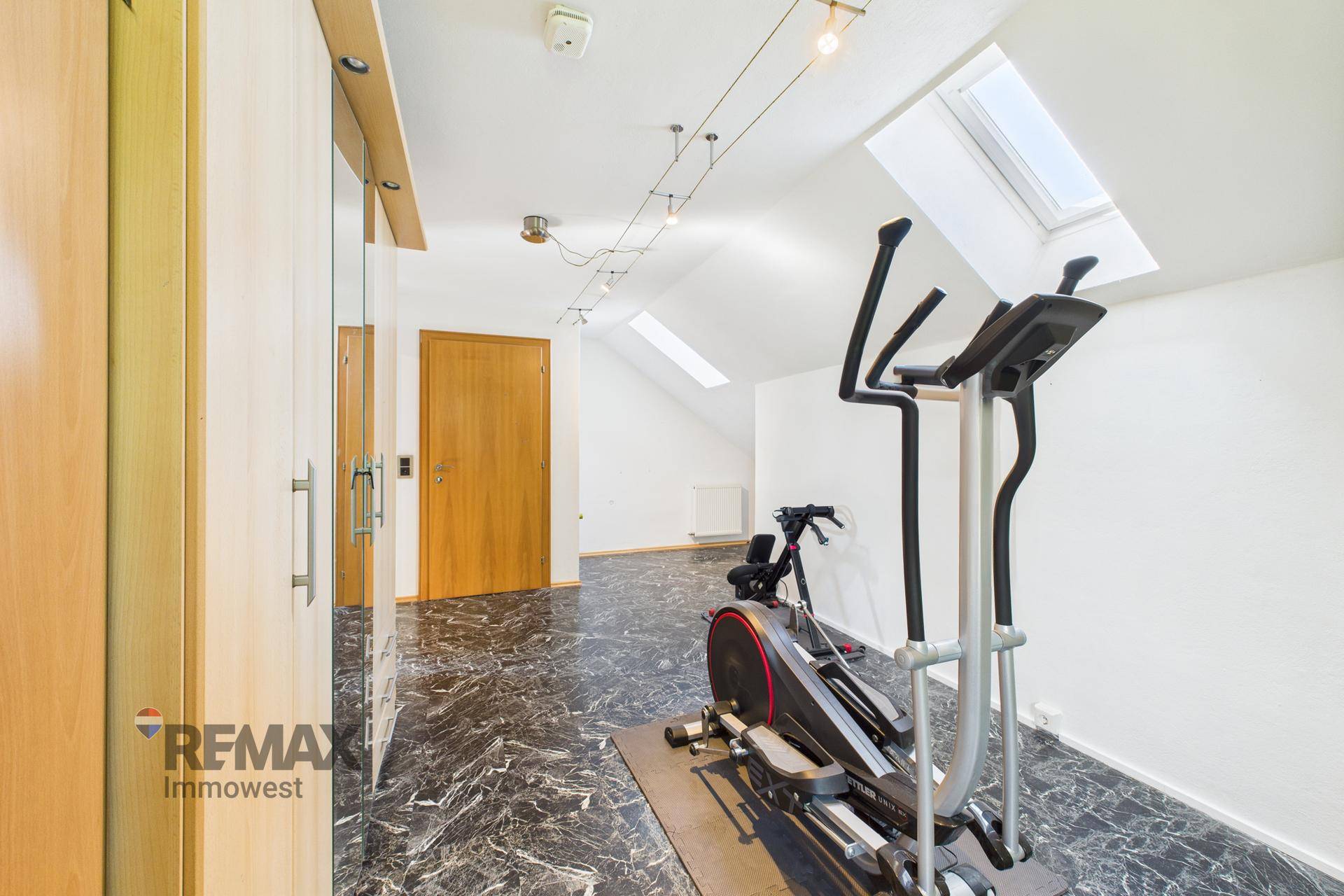 Helles Fitnesszimmer im Dachgeschoss mit Trainingsgerät, Einbauschränken und Dachfenstern.