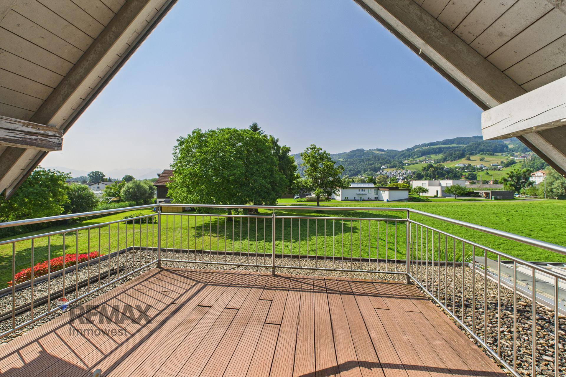 Geräumiger Balkon mit Holzbelag und weitem Blick auf die grüne Landschaft.