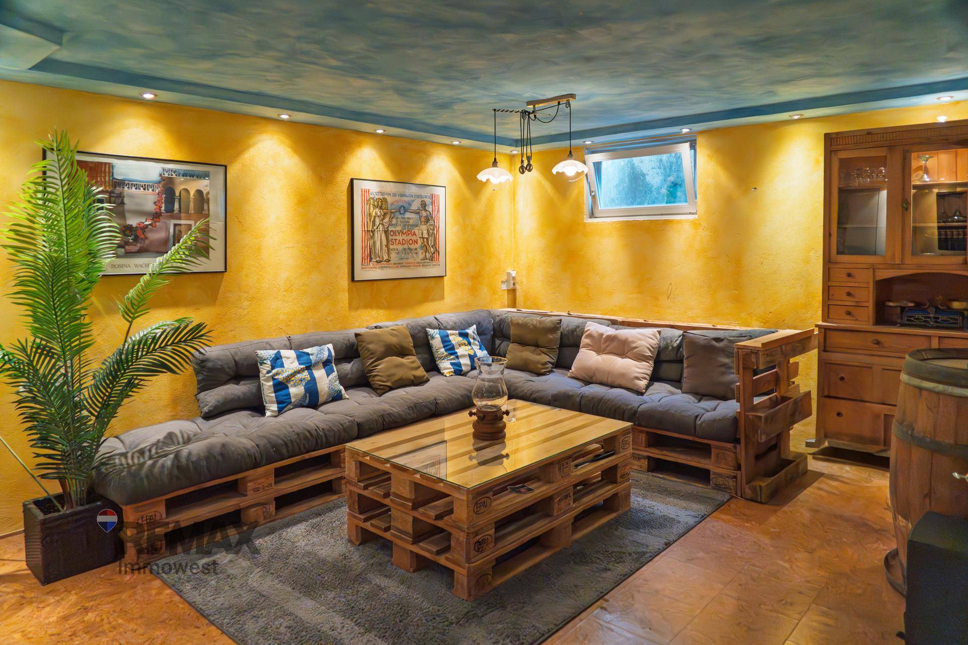 Geräumiger Wohnbereich mit großem Palettensofa, Couchtisch und farbenfroher Gestaltung.