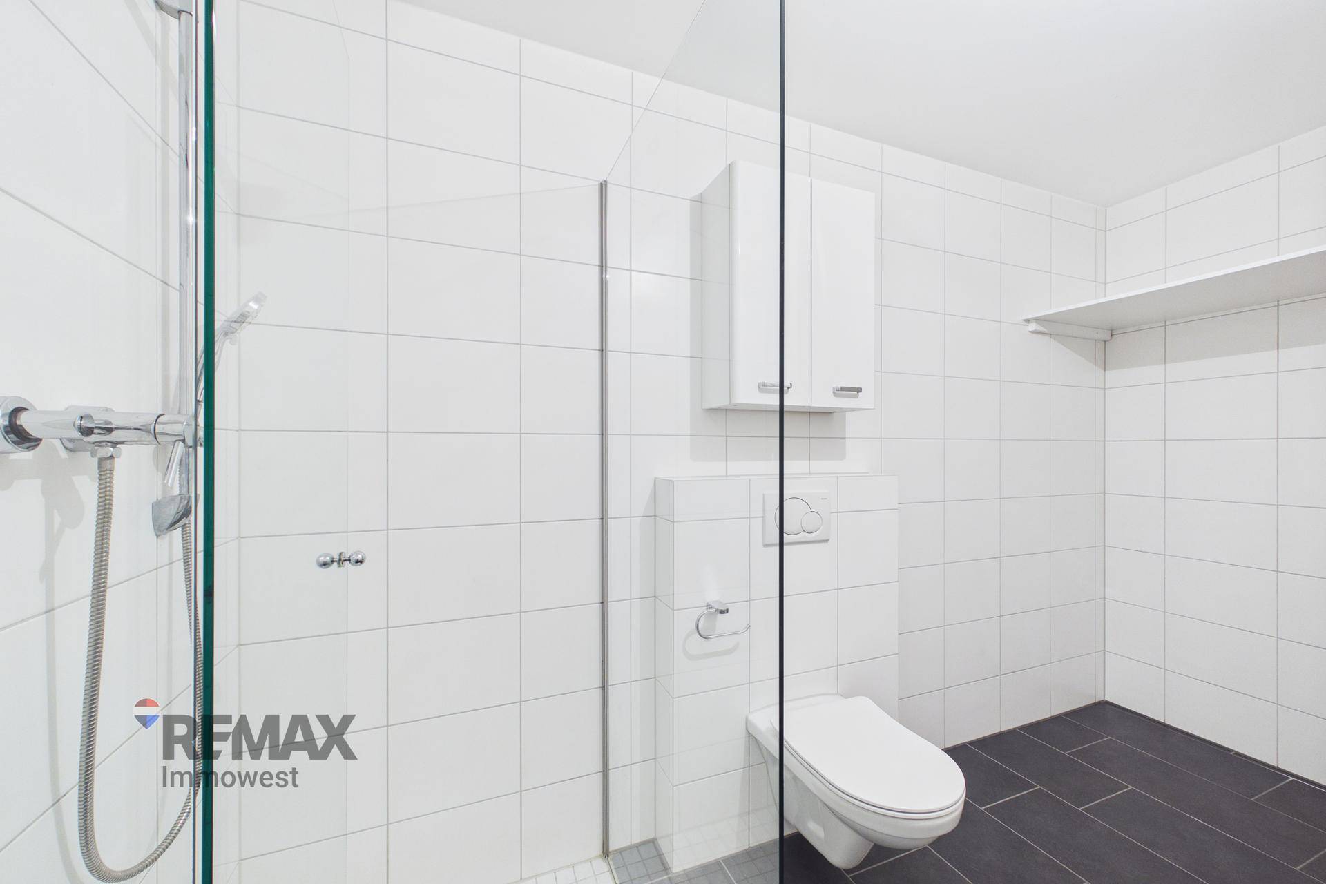 Helles Badezimmer mit großer Duschkabine, WC und Stauraum.