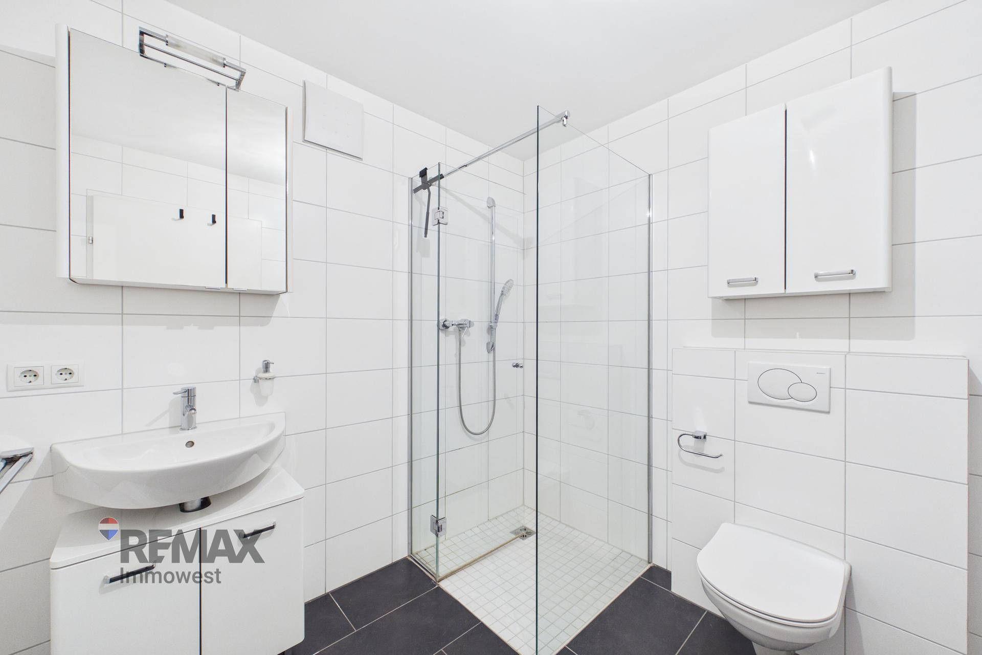 Modernes Badezimmer mit Dusche, Waschbecken und wandhängendem WC in Weiß und Grau.