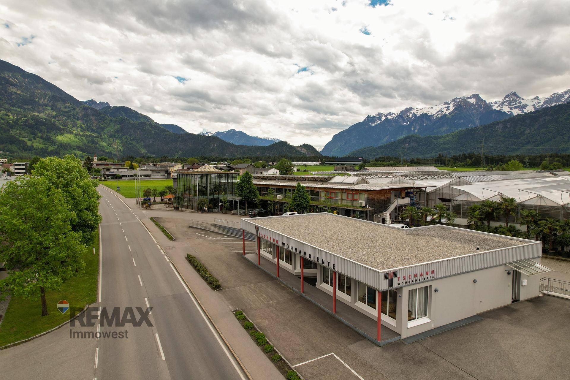 Luftaufnahme des Gewerbekomplexes mit umliegenden Grünflächen und der beeindruckenden Bergkulisse.