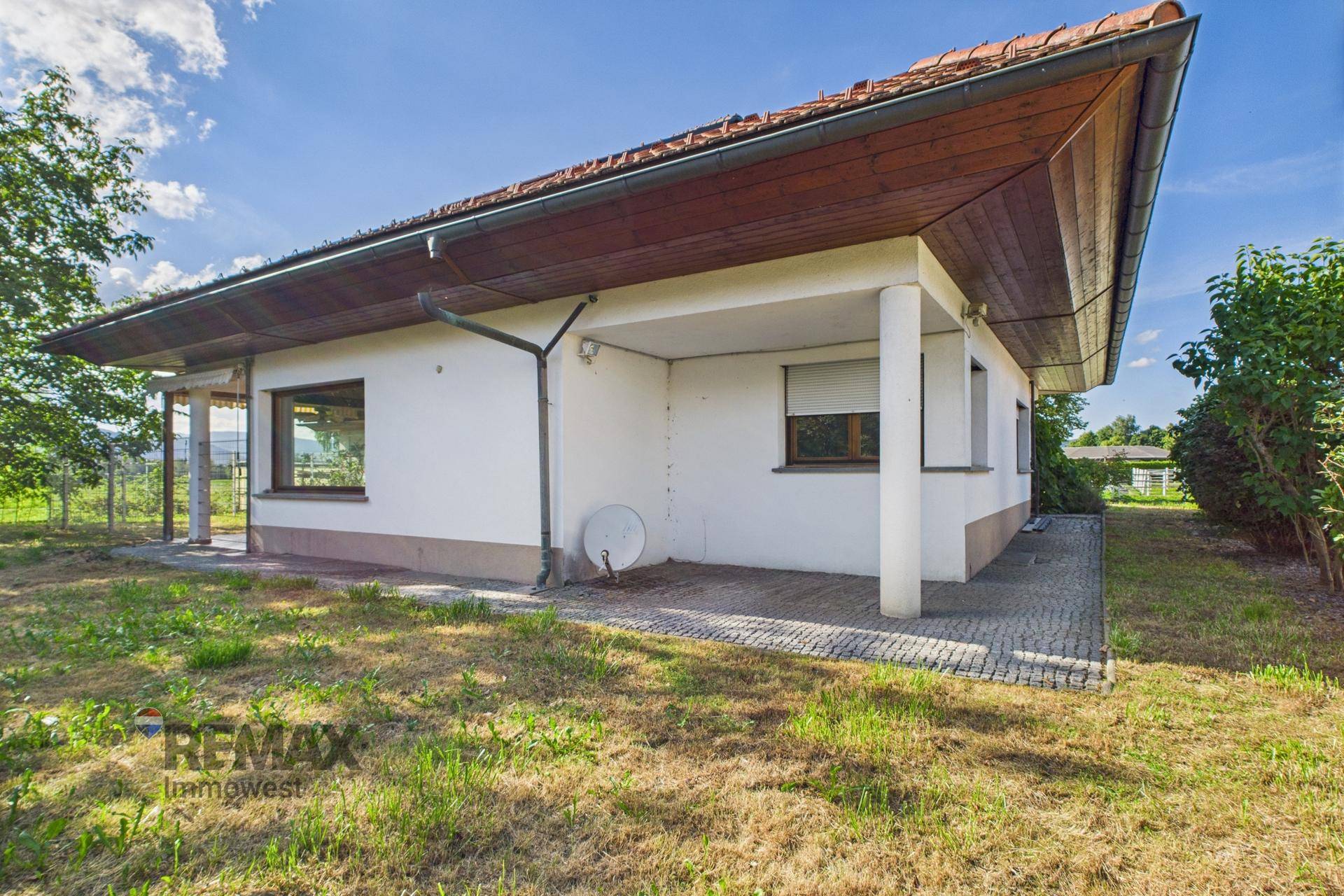 Rückseite des Hauses mit kleiner gepflasterter Fläche und Rasenfläche im Gartenbereich.
